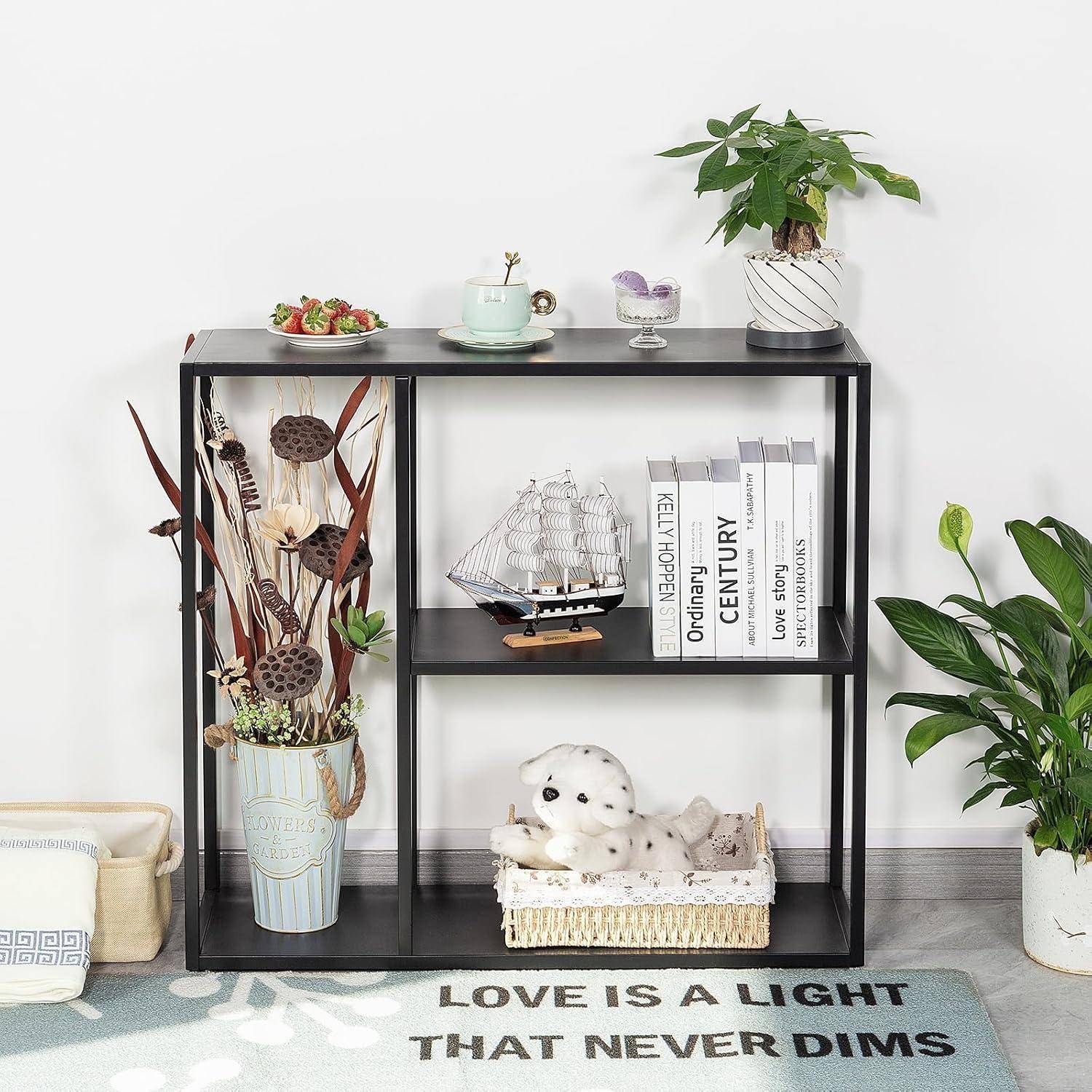 Schwarzes Regalmodul, gestylt mit Pflanzen, Büchern, Schiffsmodell, Blumen und Dekoration über einem Teppich mit der Aufschrift „LOVE IS A LIGHT THAT NEVER DIMS