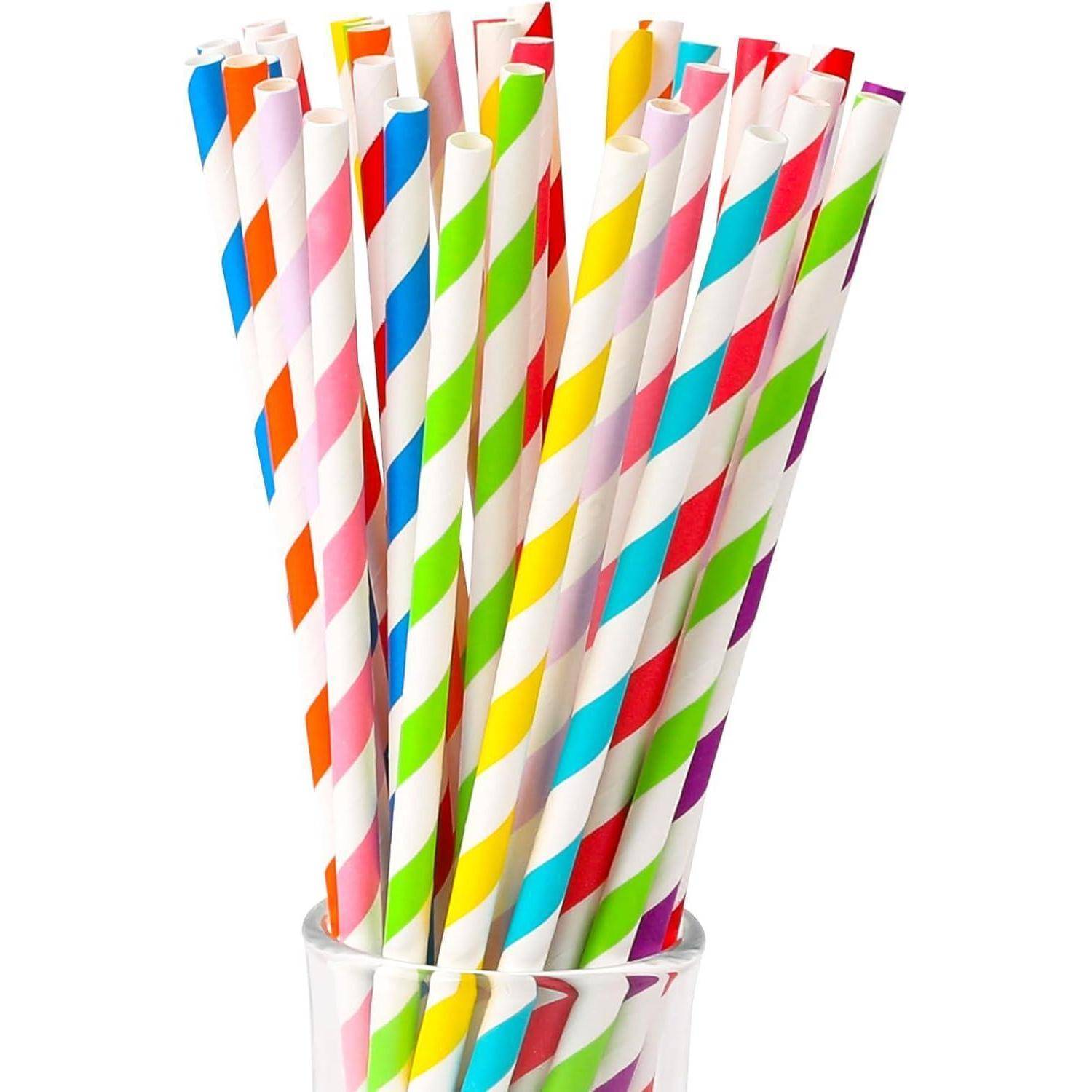 Ein Bündel bunter gestreifter Papiertrinkhalme, die in einem klaren Glas auf weißem Hintergrund stehen.