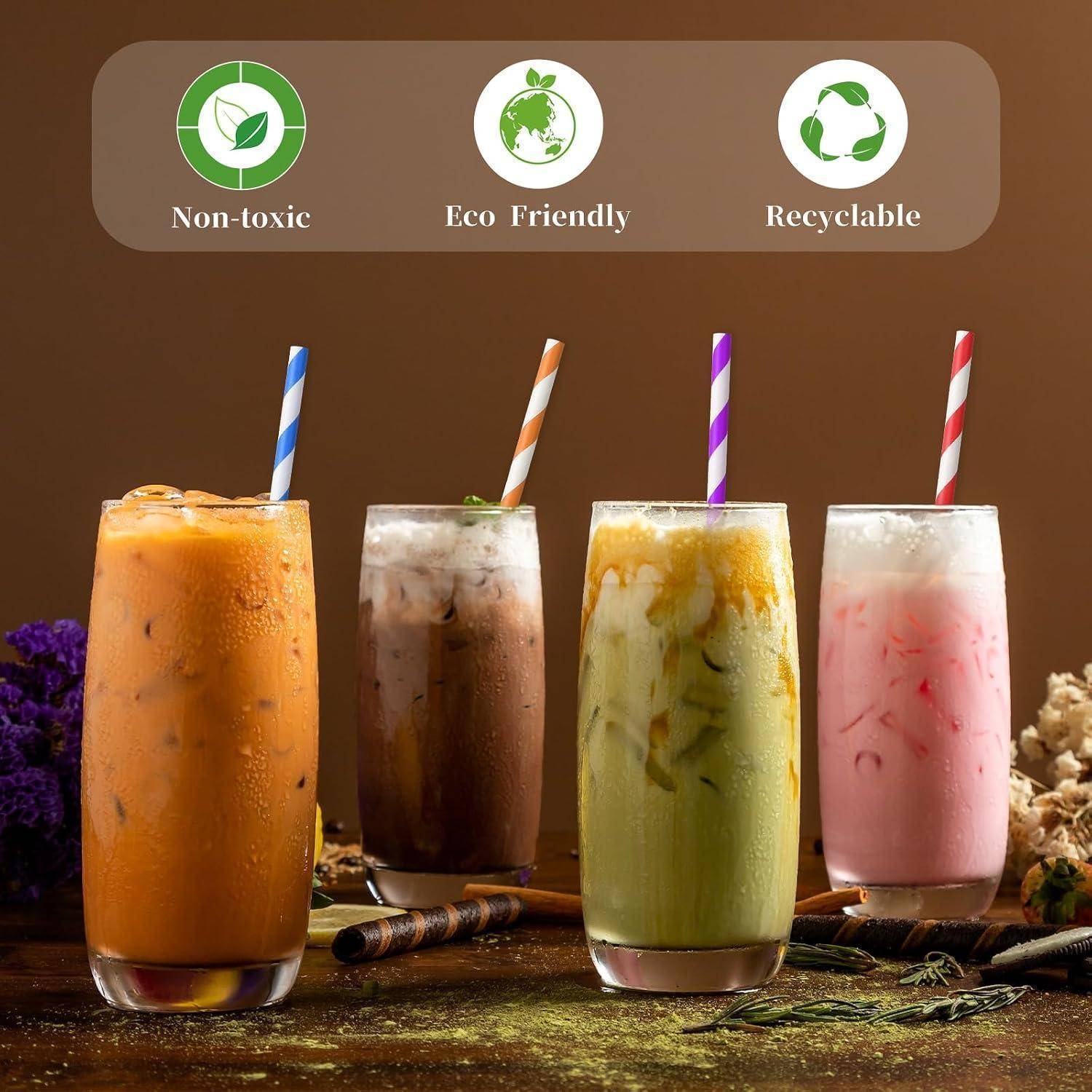 Vier eisgekühlte Getränke mit gestreiften Papierstrohhalmen werden unter Symbolen mit den Beschriftungen „Ungiftig", „Umweltfreundlich"" und „Recycelbar"" gezeigt.