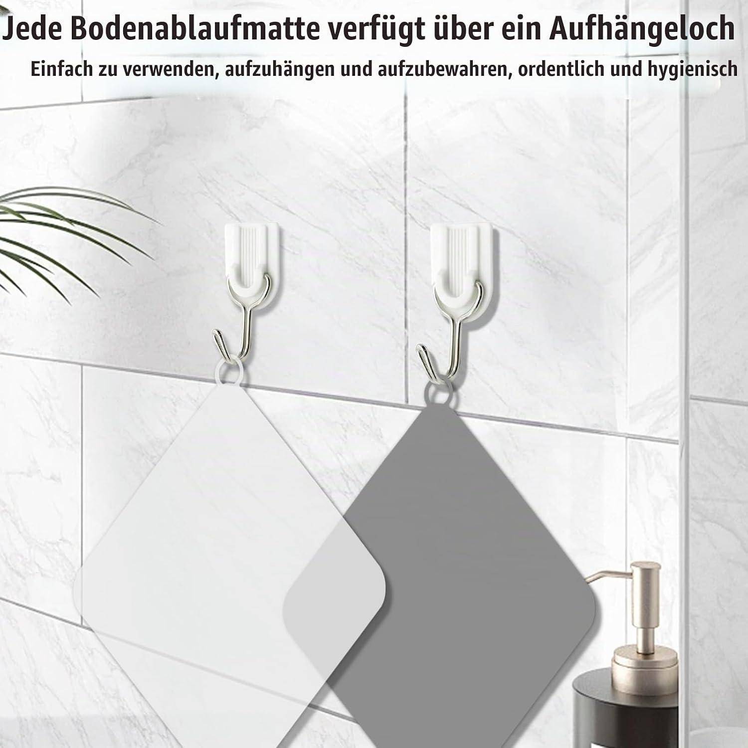 Zwei an Haken hängende rautenförmige Fußmatten mit deutschem Text, die angeben, dass jede Matte ein Aufhängeloch für einfache, hygienische Lagerung hat.