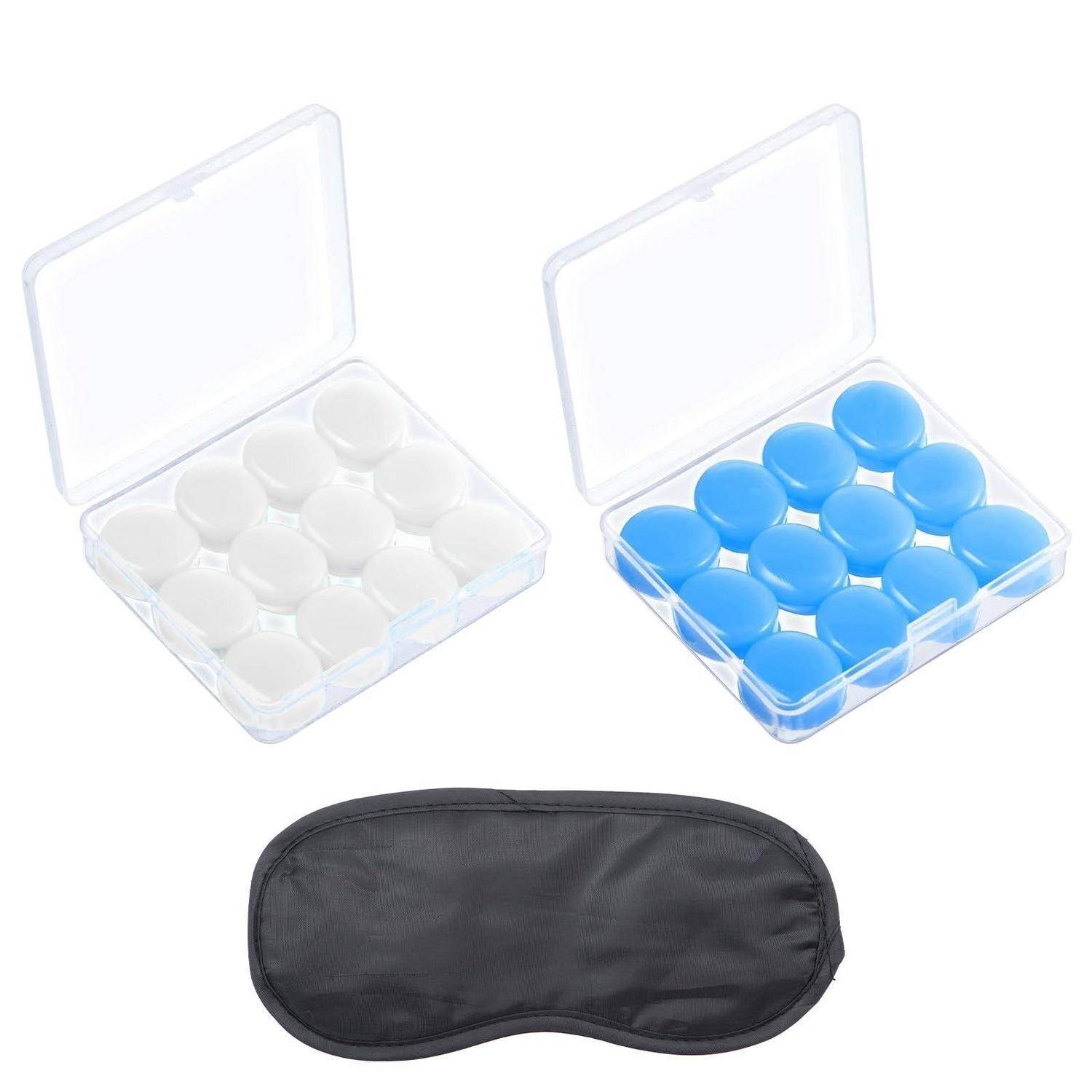 Zwei durchsichtige Pillendosen, eine mit weißen Tabletten und eine mit blauen Tabletten, über einer schwarzen Reise-Schlafmaske.