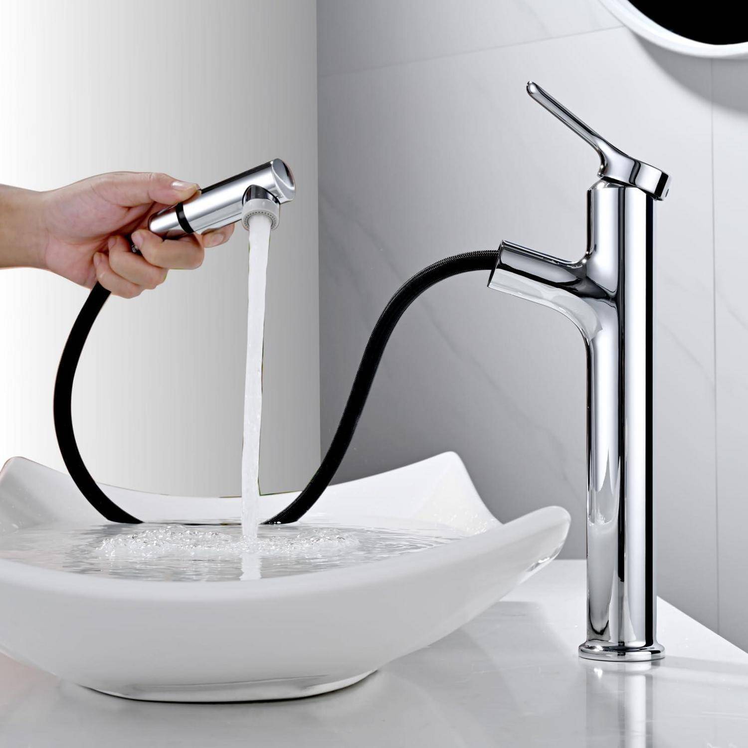 Hand hält einen chromfarbenen Wasserhahn-Sprayer, der Wasser in ein weißes Badezimmerbecken neben einem passenden hohen chromfarbenen Wasserhahn laufen lässt.