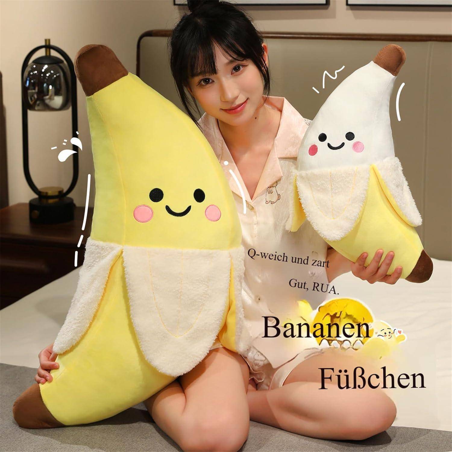 Eine Frau sitzt im Haus und hält zwei lächelnde Bananenkuscheltiere, ein großes und ein kleines, mit dem überlagerten Text „Bananen Füßchen".
