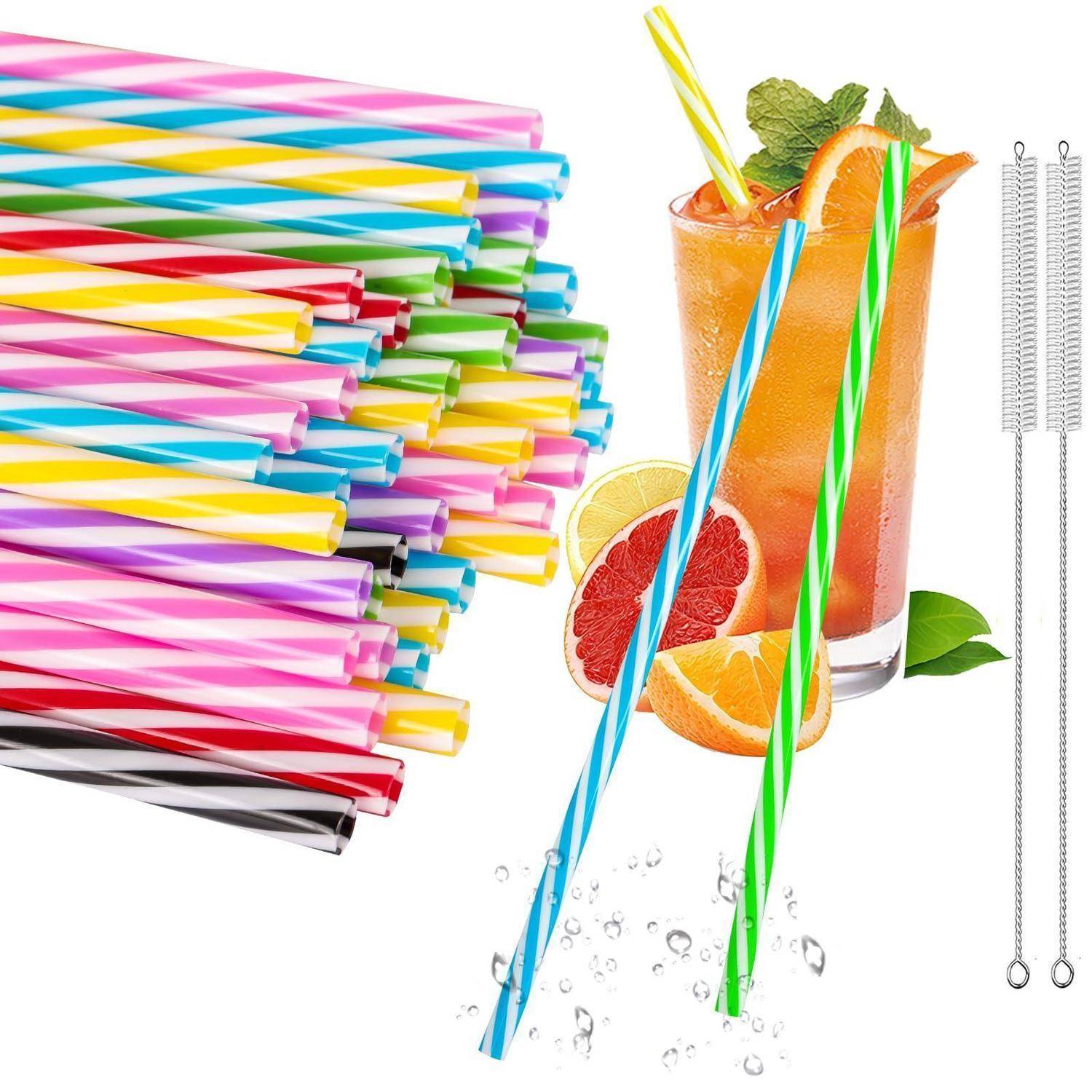Bunte gestreifte wiederverwendbare Trinkhalme neben einem Fruchtcocktail mit Zitrusscheiben sowie metallische Reinigungsbürsten auf weißem Hintergrund.