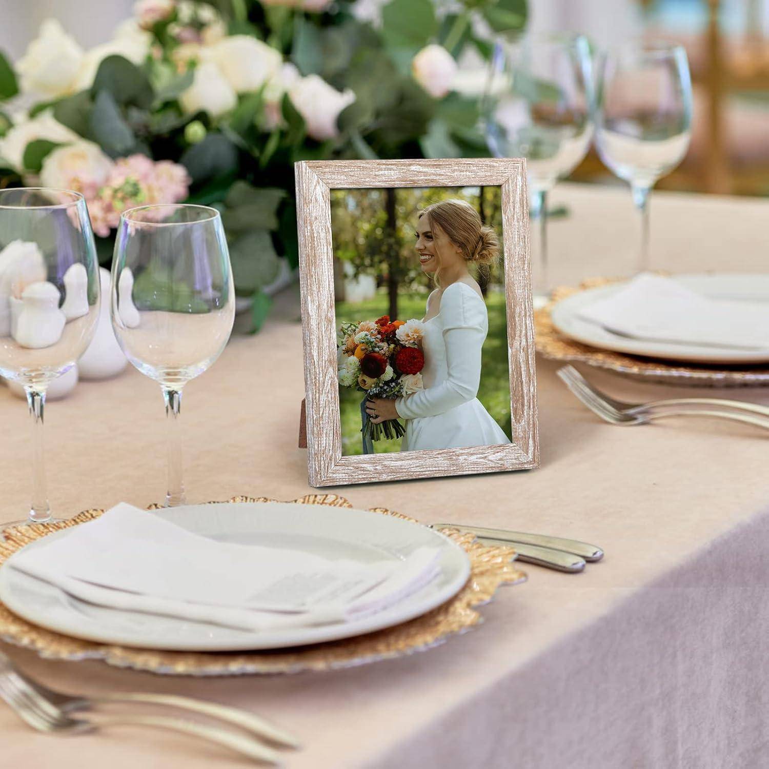 Hochzeitsempfang-Tisch mit gerahmtem Foto einer Braut, die einen Blumenstrauß hält, umgeben von Tellern, Gläsern und Blumen-Tischdekorationen.