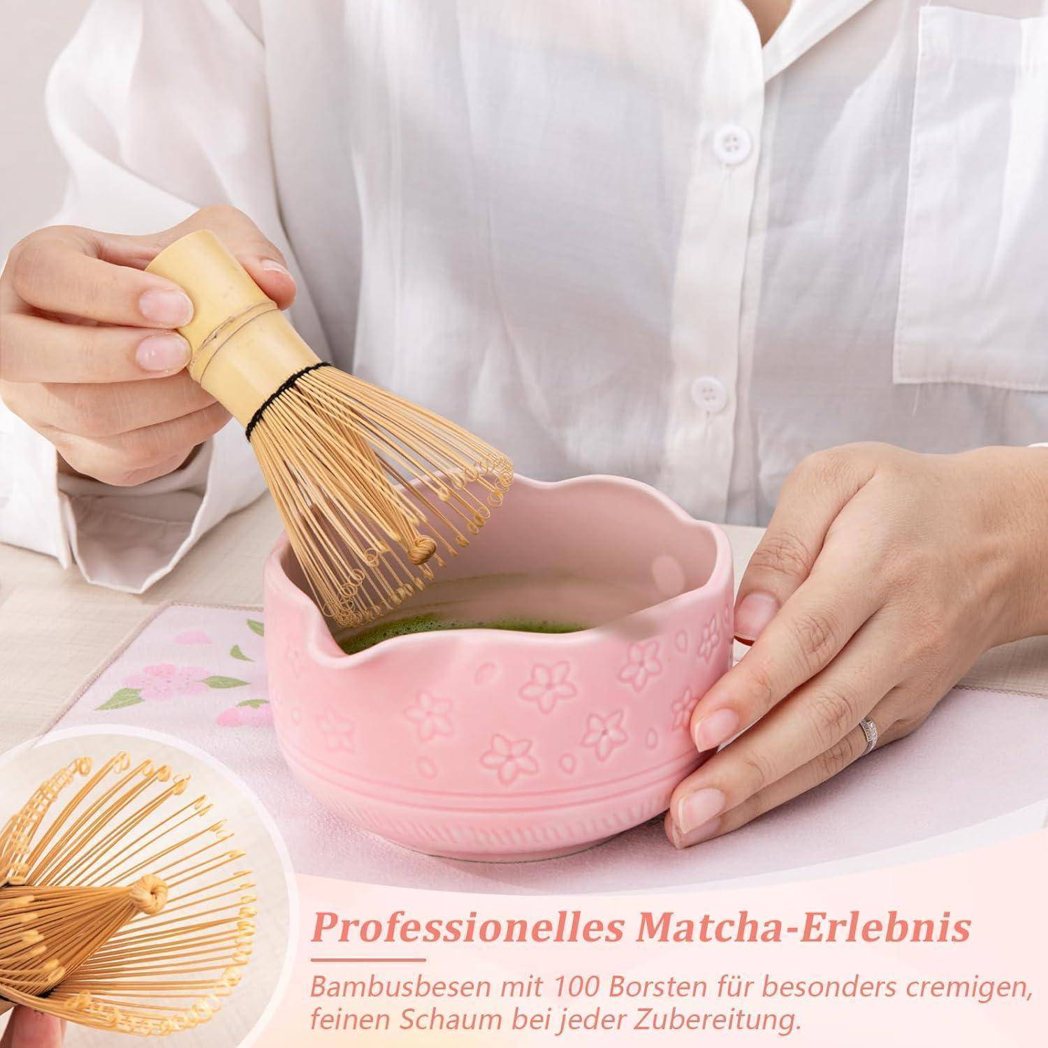 Hände schlagen Matcha in einer rosa Keramikschüssel mit einem Bambusquirl auf; Text bewirbt "Professionelles Matcha-Erlebnis"" und einen Bambusquirl mit 100 Borsten.
