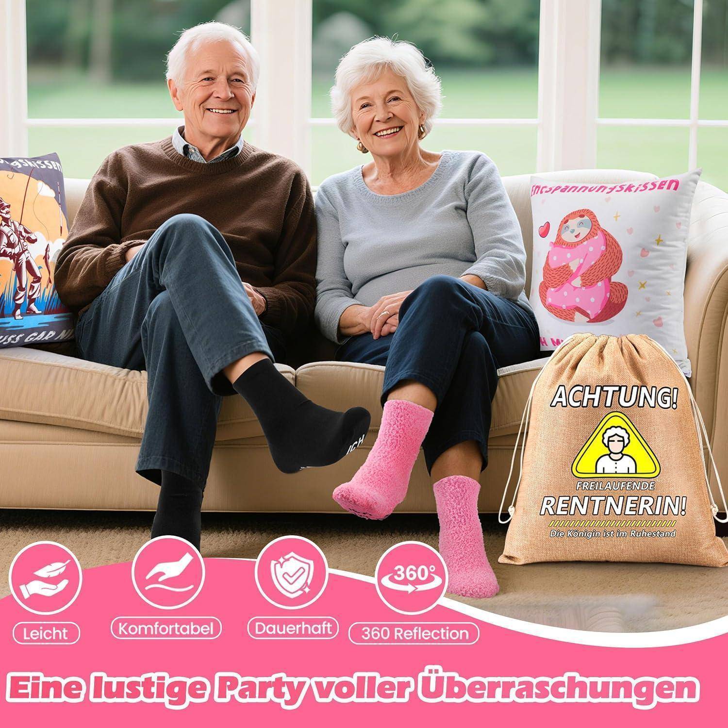 Ein lächelndes älteres Paar sitzt auf einem Sofa in einem hellen Wohnzimmer, umgeben von humorvollen Novelty-Kissen und einer Geschenktasche mit der Aufschrift „ACHTUNG! FREIFAHRENDE RENTNERIN!