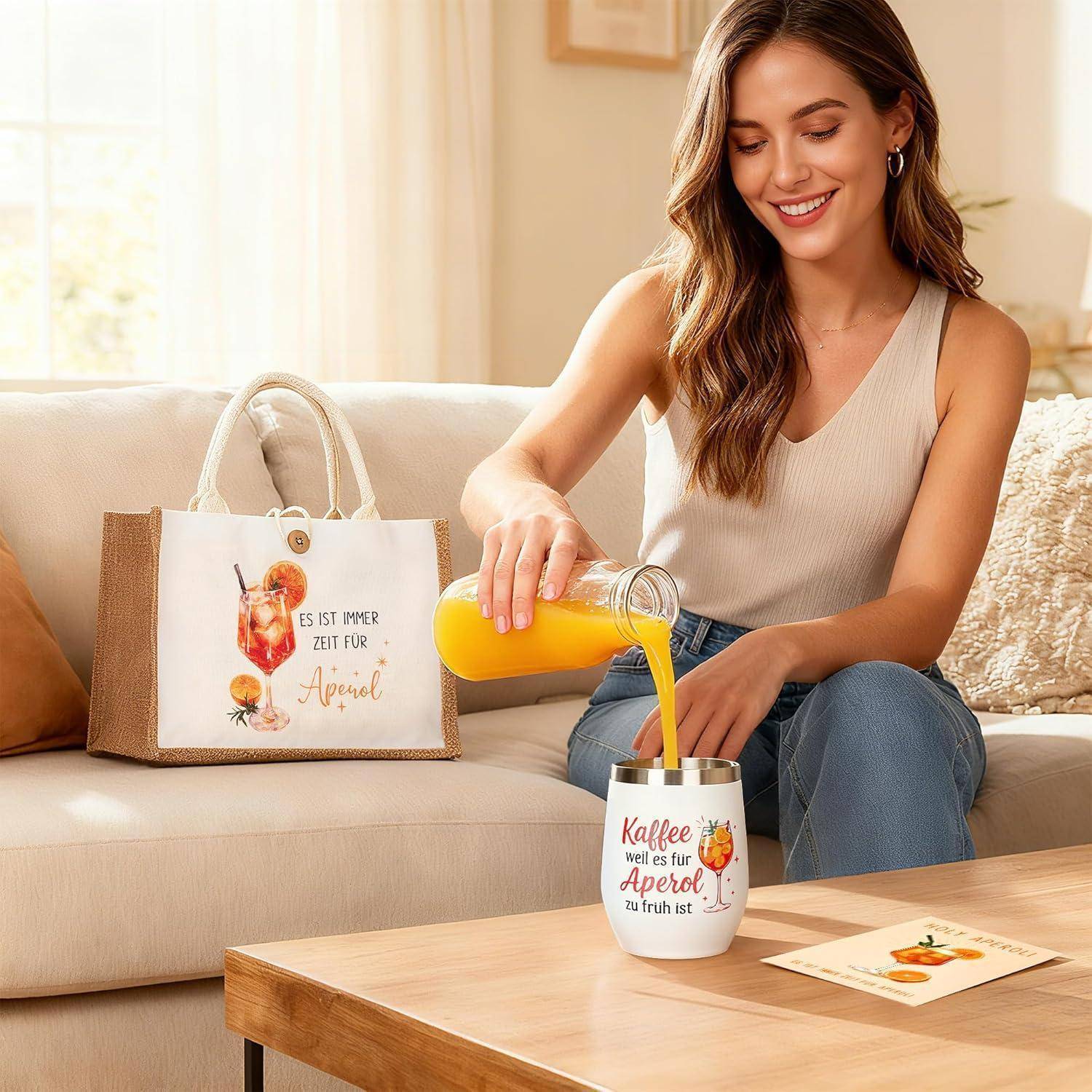 Eine Frau gießt Orangensaft in eine Tasse auf einem Sofa, neben einer Tragetasche und einer Karte mit deutschem „Aperol"-Design.