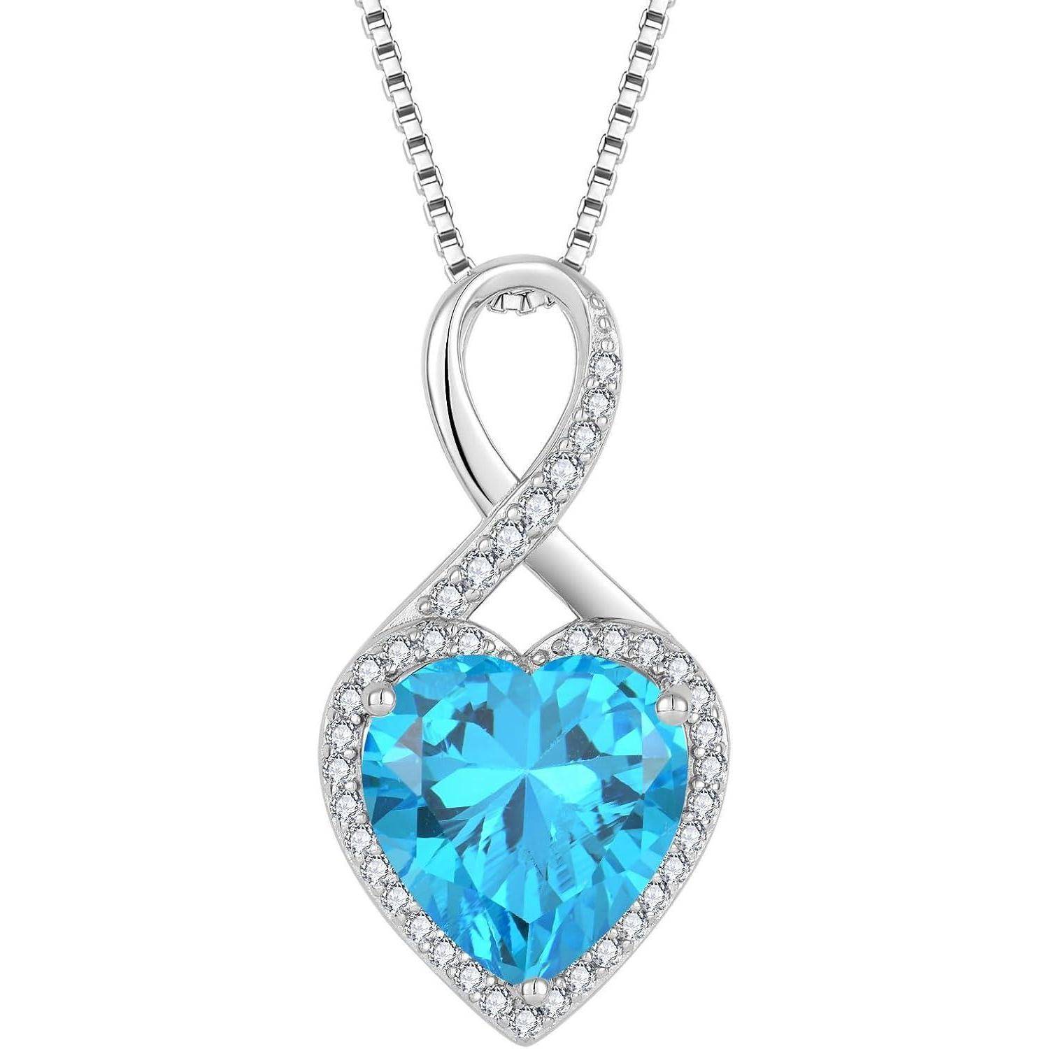 Silberne herzförmige Anhängerkette mit einem blauen Edelstein in der Mitte und kleinen klaren Steinen, hängend an einer Kette.