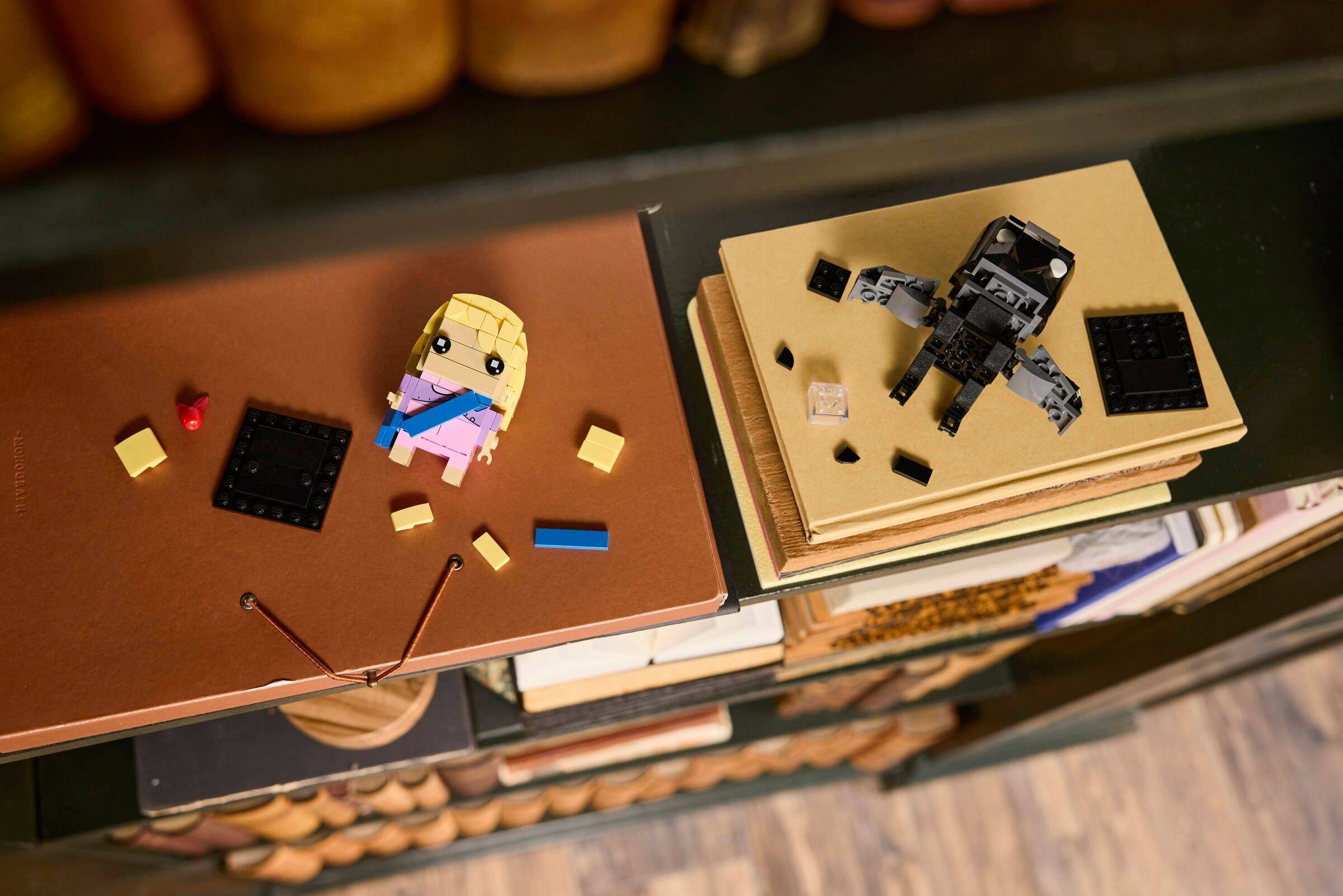 Zwei LEGO-ähnliche Notizbuchcover auf Anzeige: ein braunes Cover mit einer blonden Figur und verstreuten Teilen, ein beiges Cover mit einer schwarzen Roboterfigur.