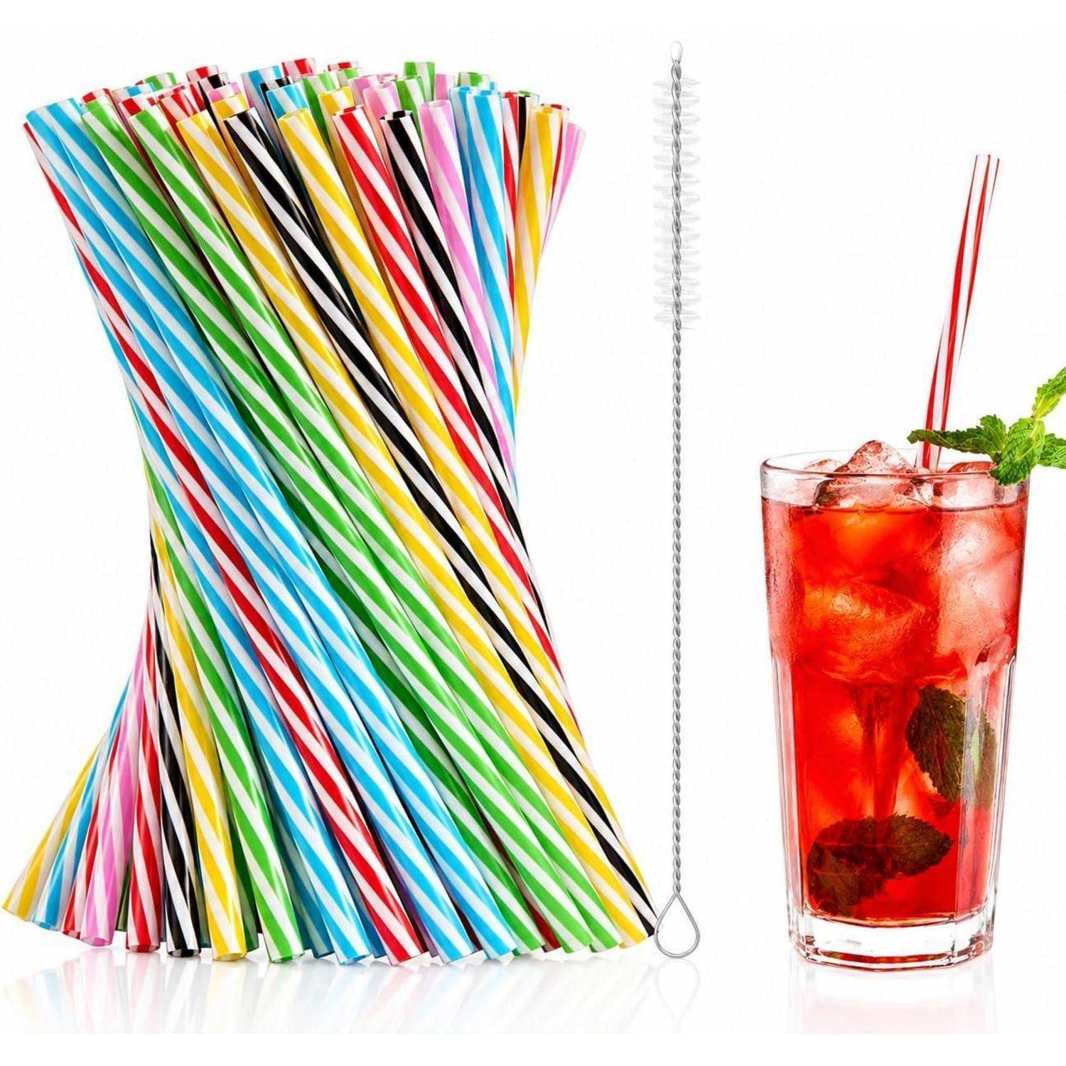 Bunte gestreifte Trinkhalme, eine lange Reinigungsbürste und ein Glas mit rotem Eiskaltgetränk mit zwei Halmen und Minzgarnitur.