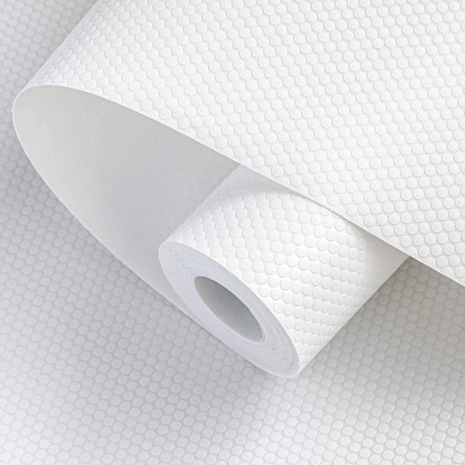 Nahaufnahme einer Rolle aus weißem strukturiertem Material mit einem kreisförmigen Punktmuster, das auf einer entsprechenden Oberfläche teilweise abgerollt ist.