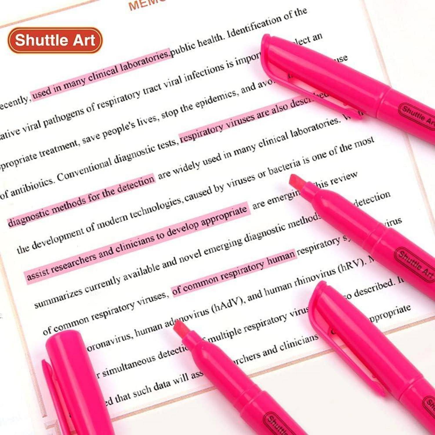 Rosa Textmarker markieren Text auf einer gedruckten Seite, wobei mehrere neonrosa Marker über das Dokument verteilt liegen.