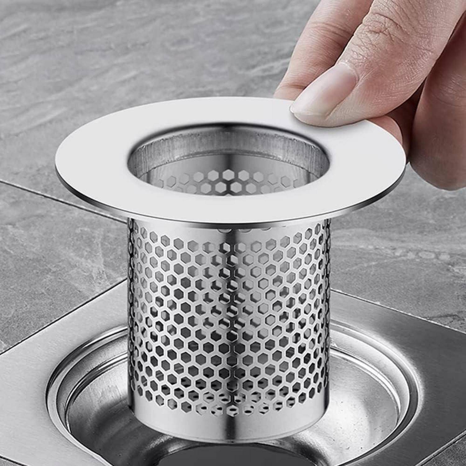 Hand platziert ein Edelstahl-Spülbeckensieb mit einem perforierten Korb in eine Bodenablaufausöffnung.