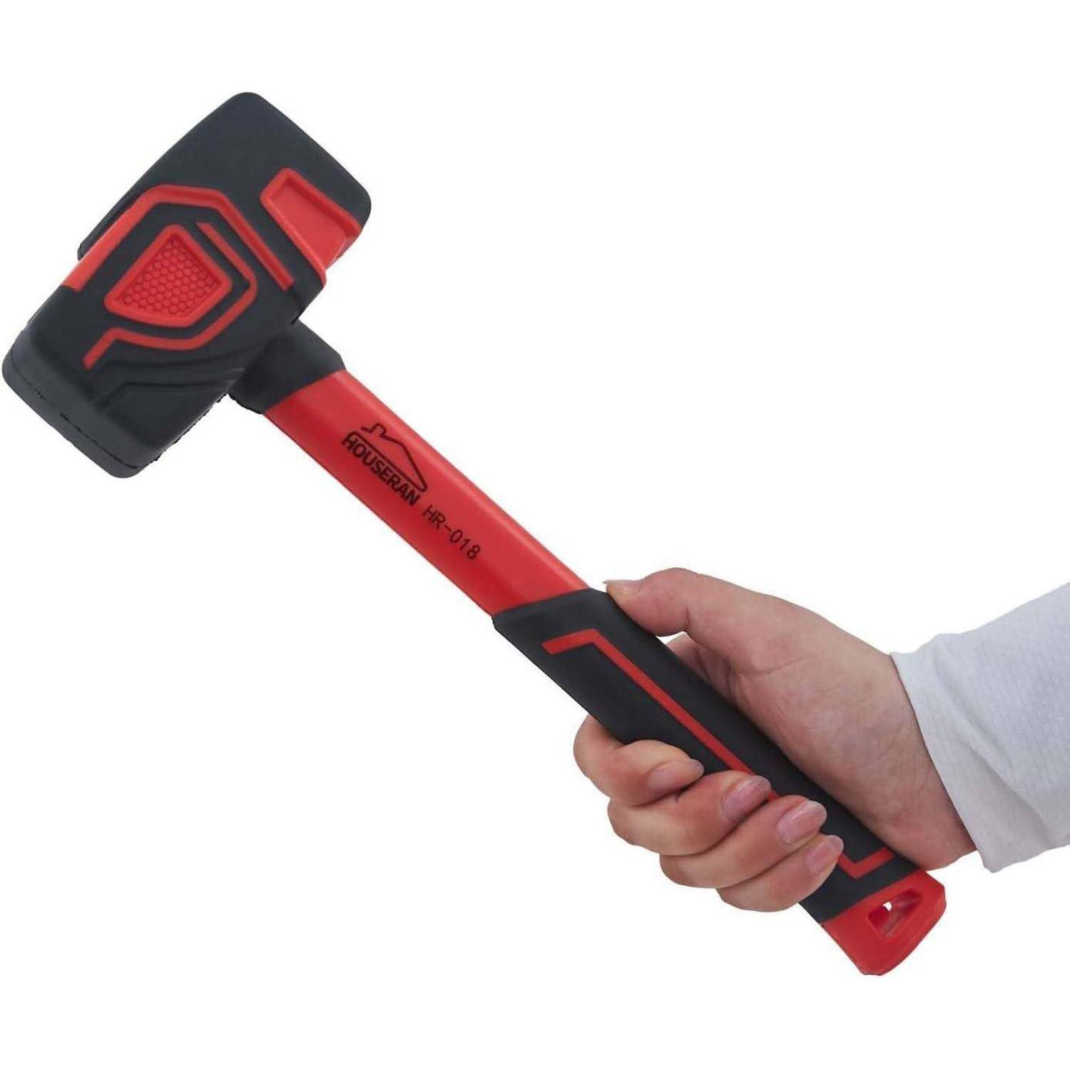 Eine Hand hält einen rot-schwarzen Gummihammer mit doppelseitigem Kopf auf weißem Hintergrund.