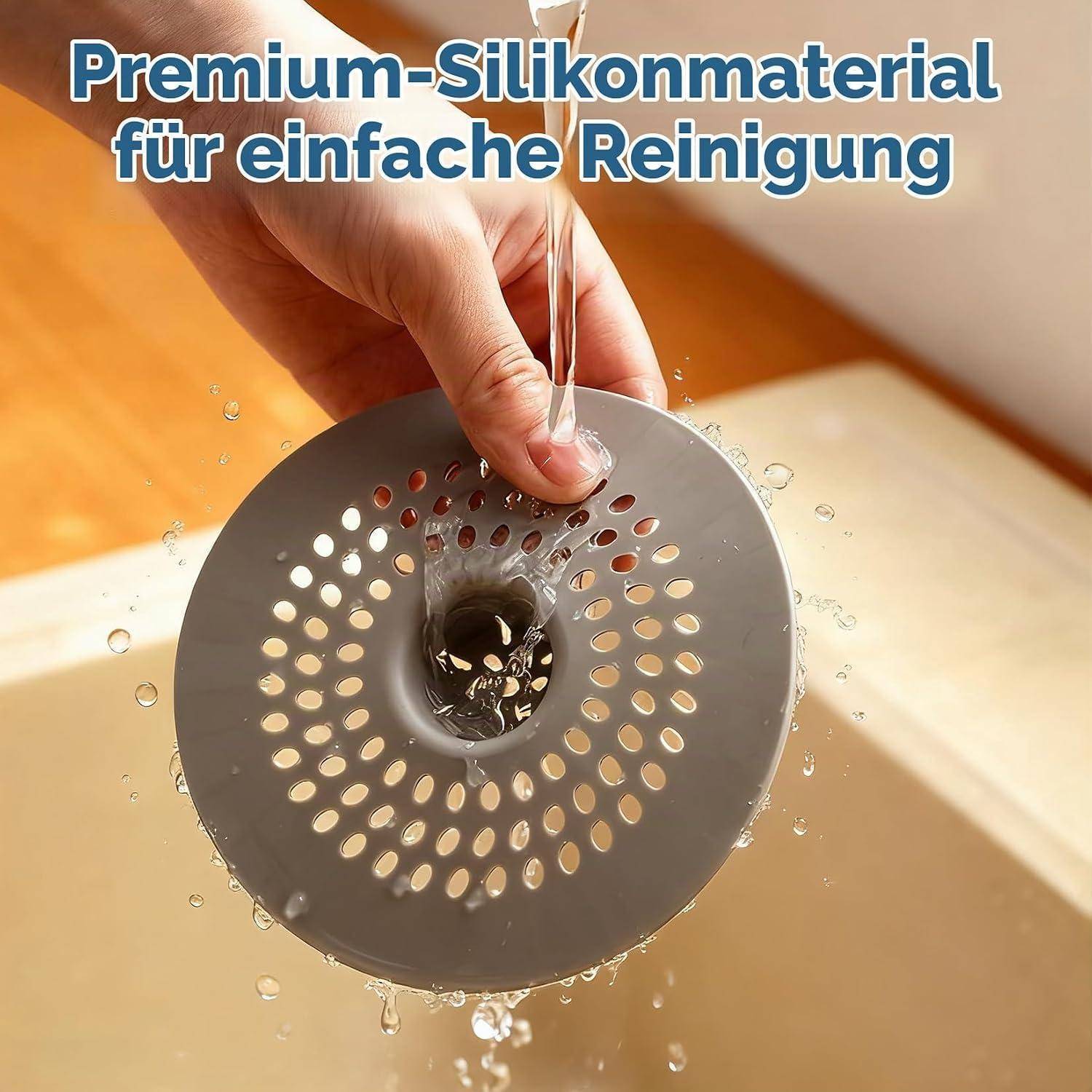 Hand hält eine graue perforierte Silikonablaufabdeckung unter fließendes Wasser; Text sagt „Premium-Silikonmaterial für einfache Reinigung".