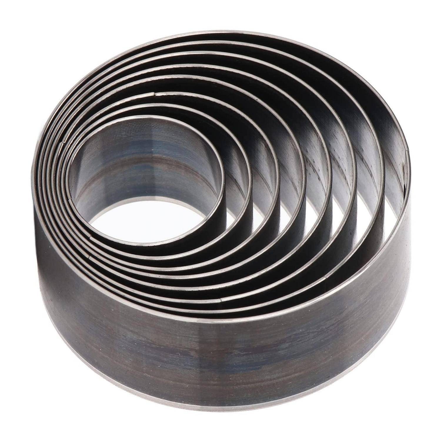 Ein Stapel verschachtelter kreisförmiger Metallringe, wie eine Industriespule oder ein Wälzlagerkäfig, auf weißem Hintergrund dargestellt.