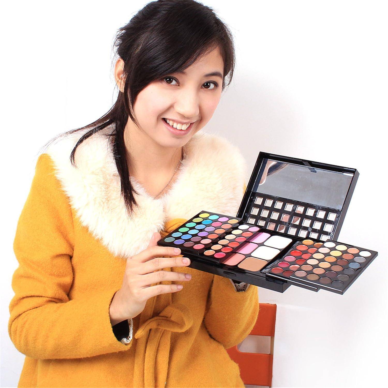 Lächelnde Frau in einem orangefarbenen Mantel, die offene Make-up-Paletten mit farbenfrohem Lidschatten und Pinseln vor einem weißen Hintergrund hält.