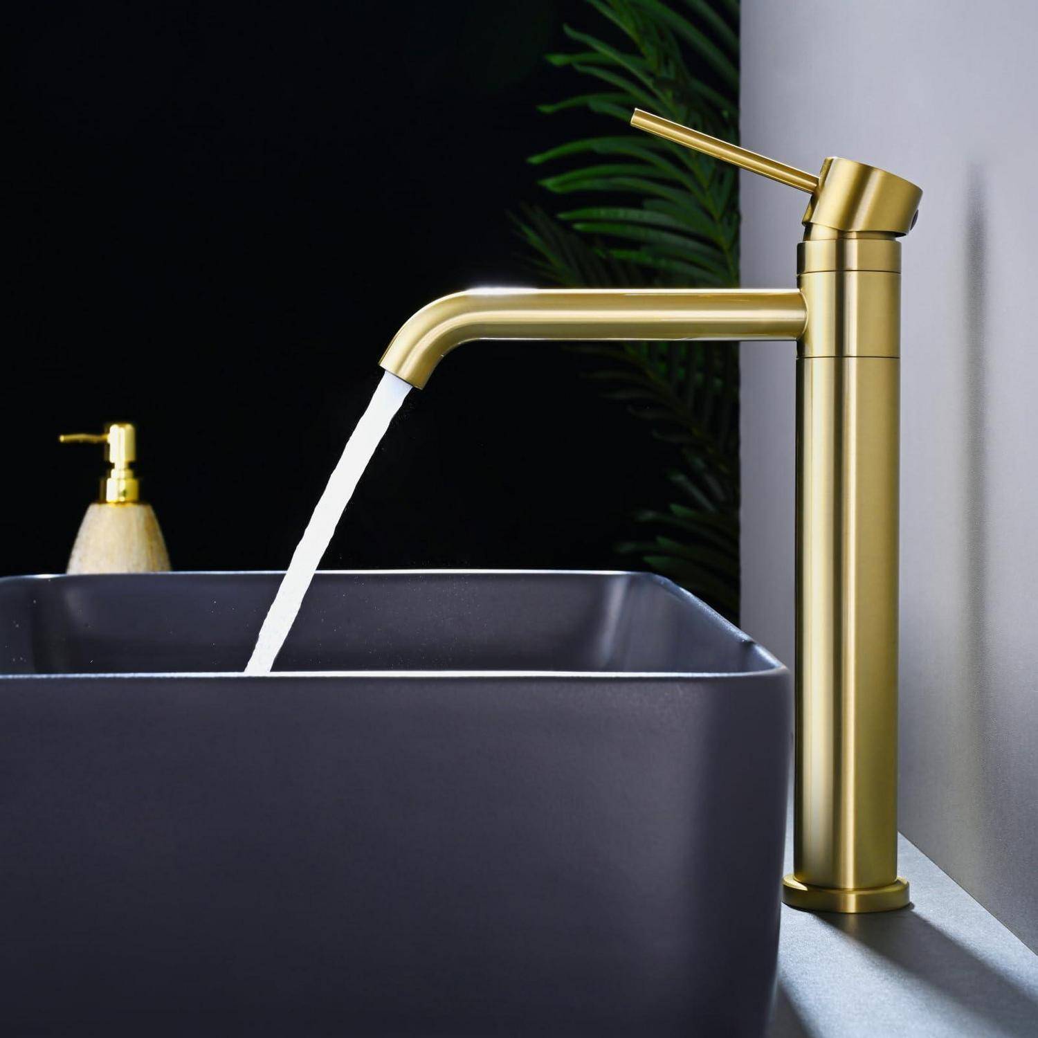 Goldfarbener Badezimmerhahn, der Wasser in ein dunkles rechteckiges Waschbecken in einer modernen Waschtischanlage gießt.