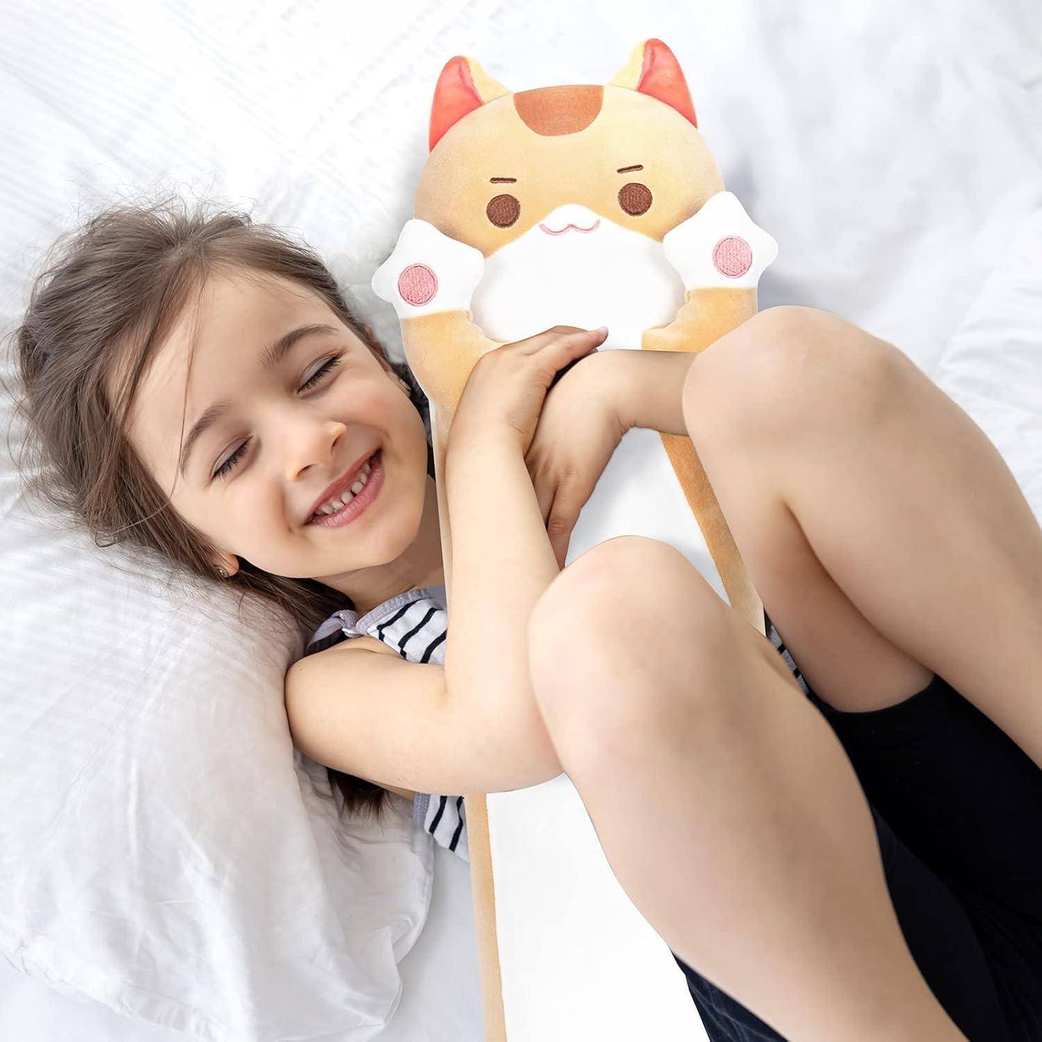 Lächelndes junges Mädchen, das auf einem Bett liegt und ein weiches Katzen-Spielzeugkissen umarmt.