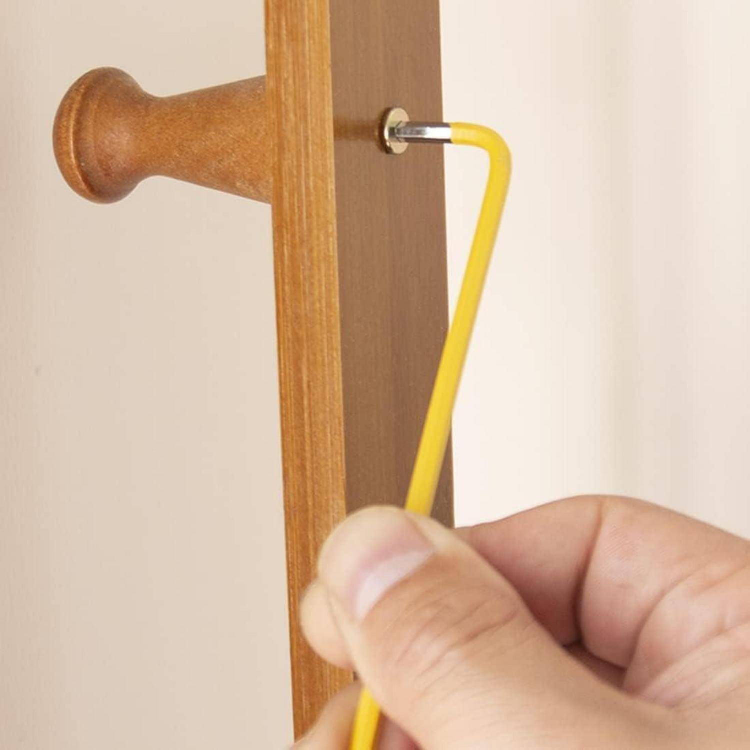 Hand, die einen gelben Sechskantschlüssel verwendet, um eine Schraube in einer Holzmöbelverbindung festzuziehen.