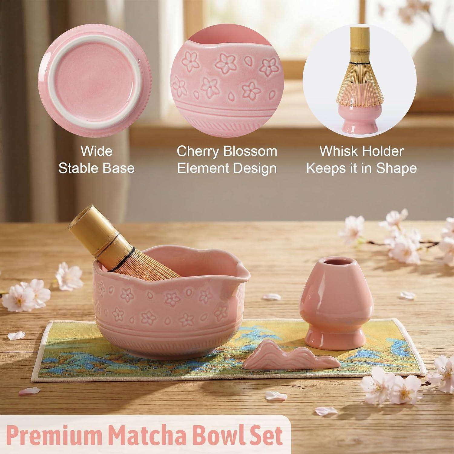 Rosa Premium-Matcha-Schale mit Schneebesen-Halter, breiter stabiler Basis und Kirschblütendesign auf einem Holztisch.