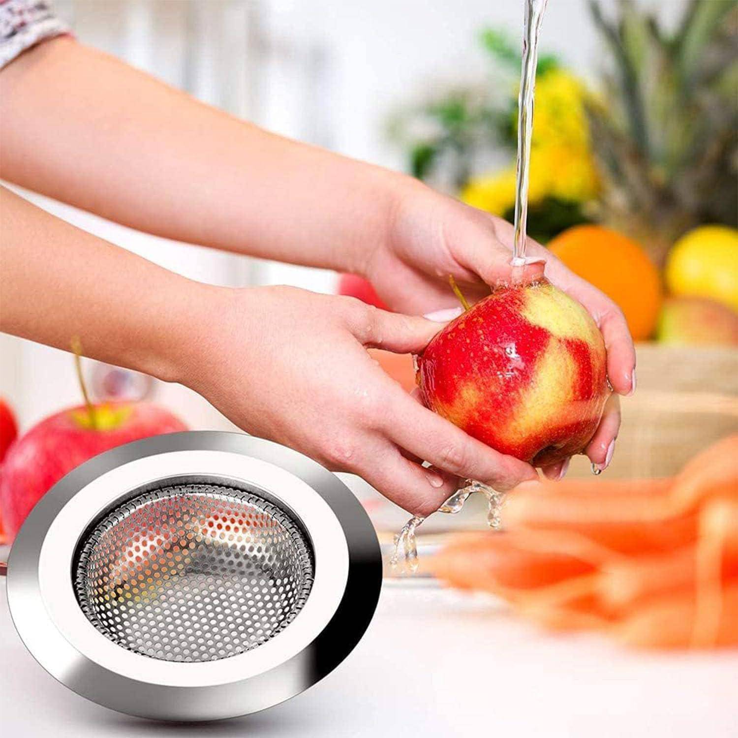 Hände waschen einen roten Apfel unter fließendem Wasser, mit einem Metallsieb-Abflusssieb der Spüle als Einsatz, was auf die Reinigung bei der Lebensmittelzubereitung hindeutet.