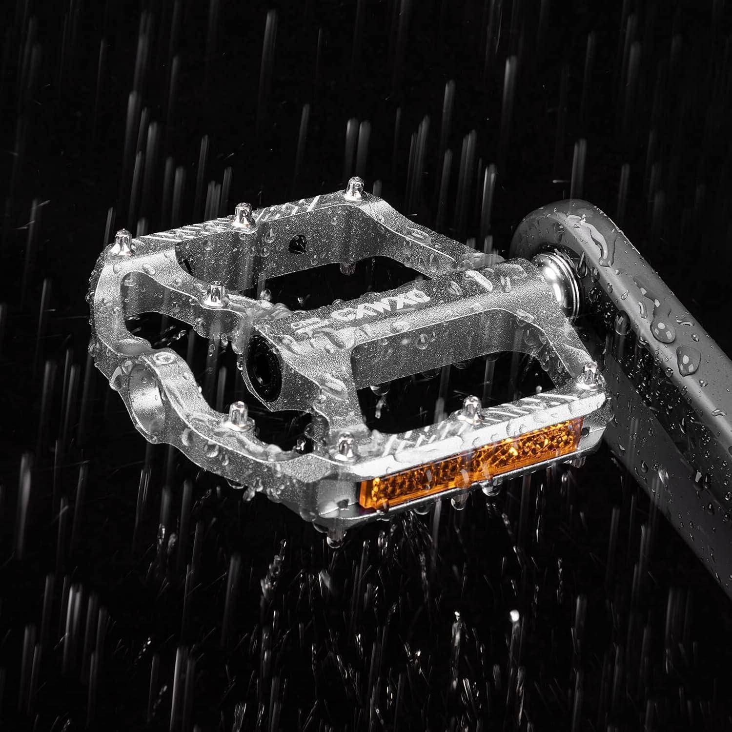 Wasserdichtes Metall-Fahrradpedal mit orangem Reflektor, gezeigt im Regen auf einem Kurbelarm.