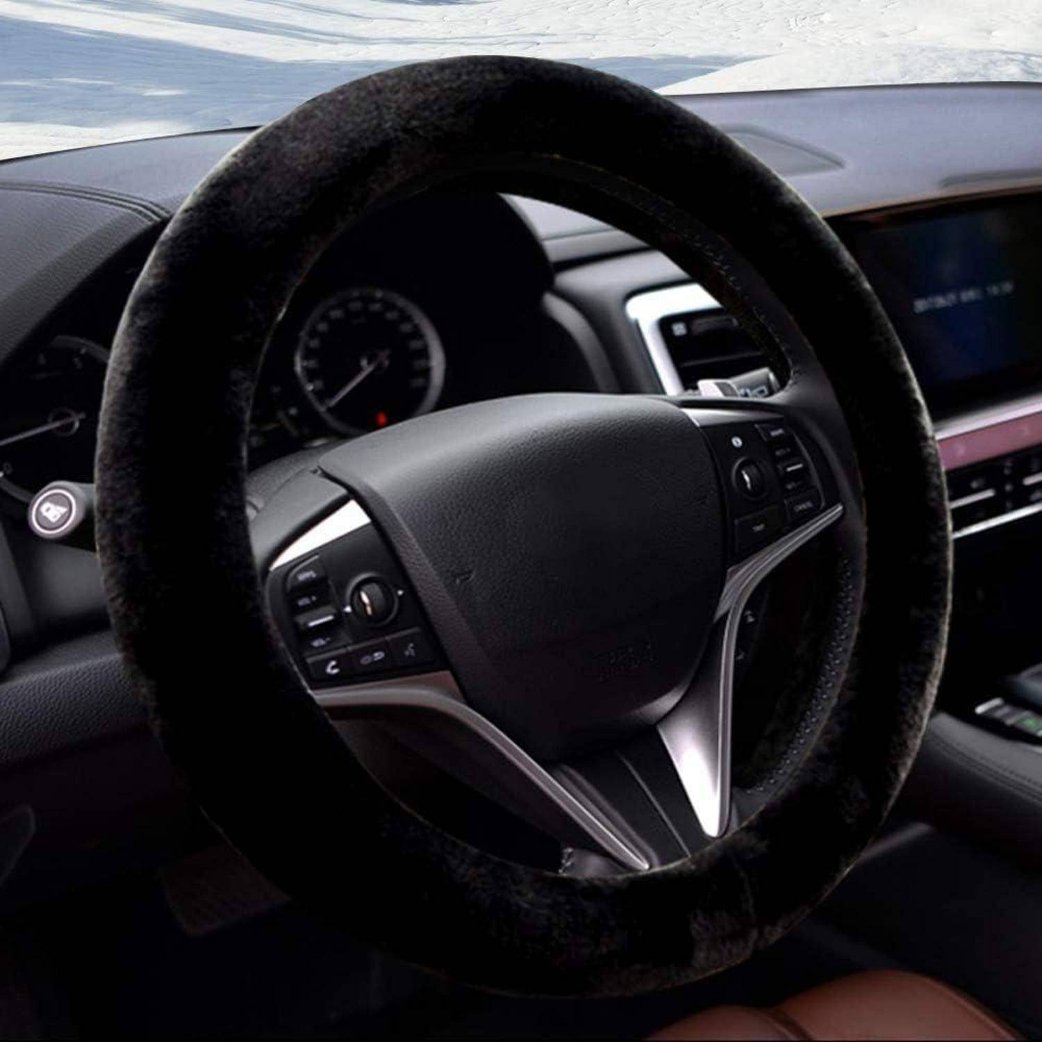 Nahaufnahme eines Autolenkrads mit schwarzem Flauschbezug, zeigt Armaturenbrettregler und zentrales Display im Fahrzeuginnenraum.