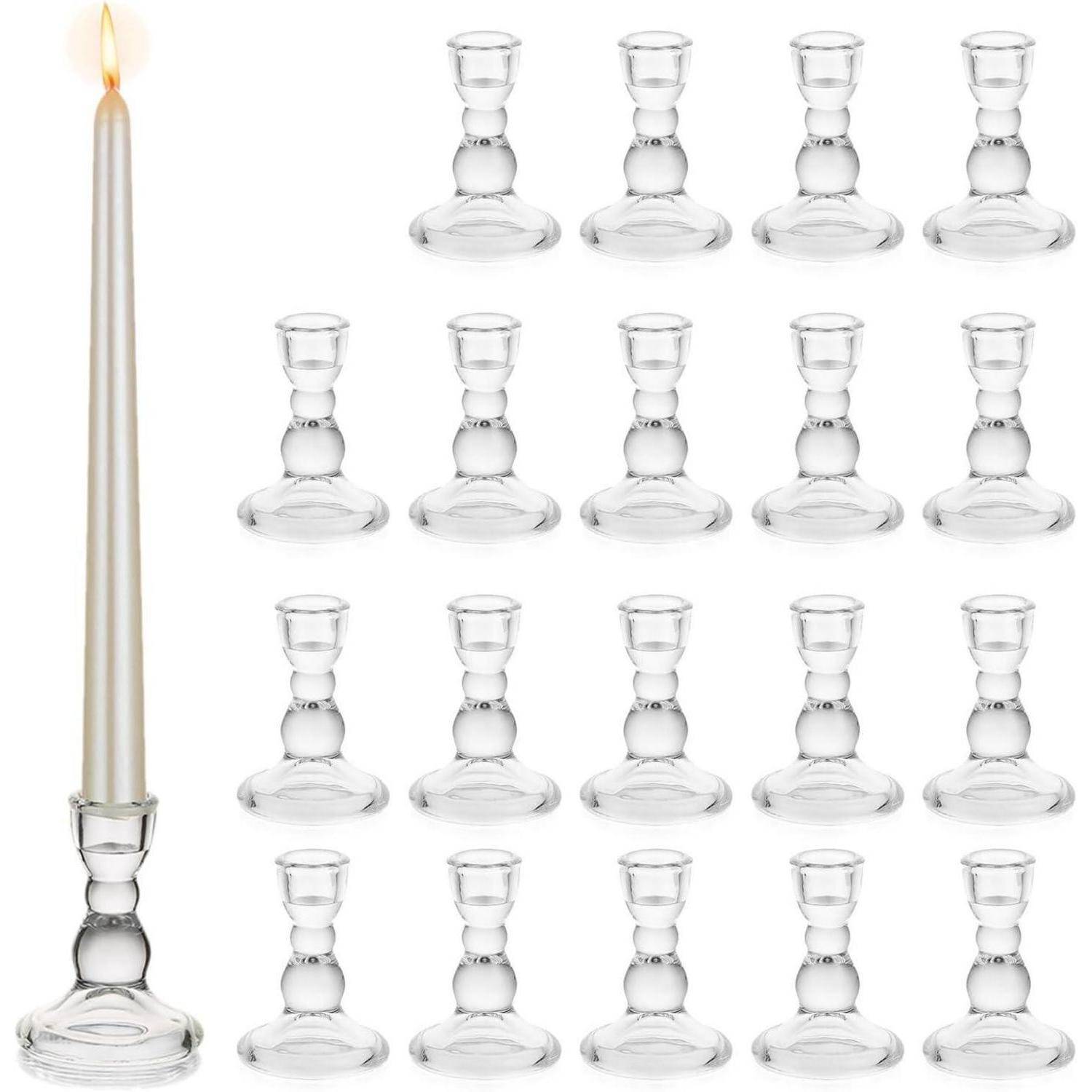 Eine brennende Kerze in einem Glashalter neben einem Raster identischer leerer Kristallkerzenhalter.
