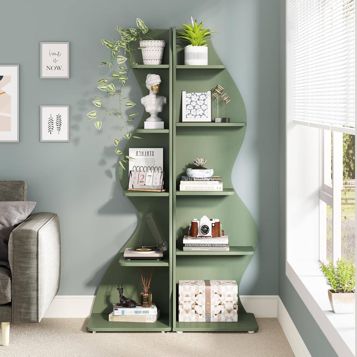 Grünes blattförmiges Bücherregal mit Regalen, die Bücher, Pflanzen, eine Büste und Deko neben einem Fenster in einem hellen Wohnzimmer halten.