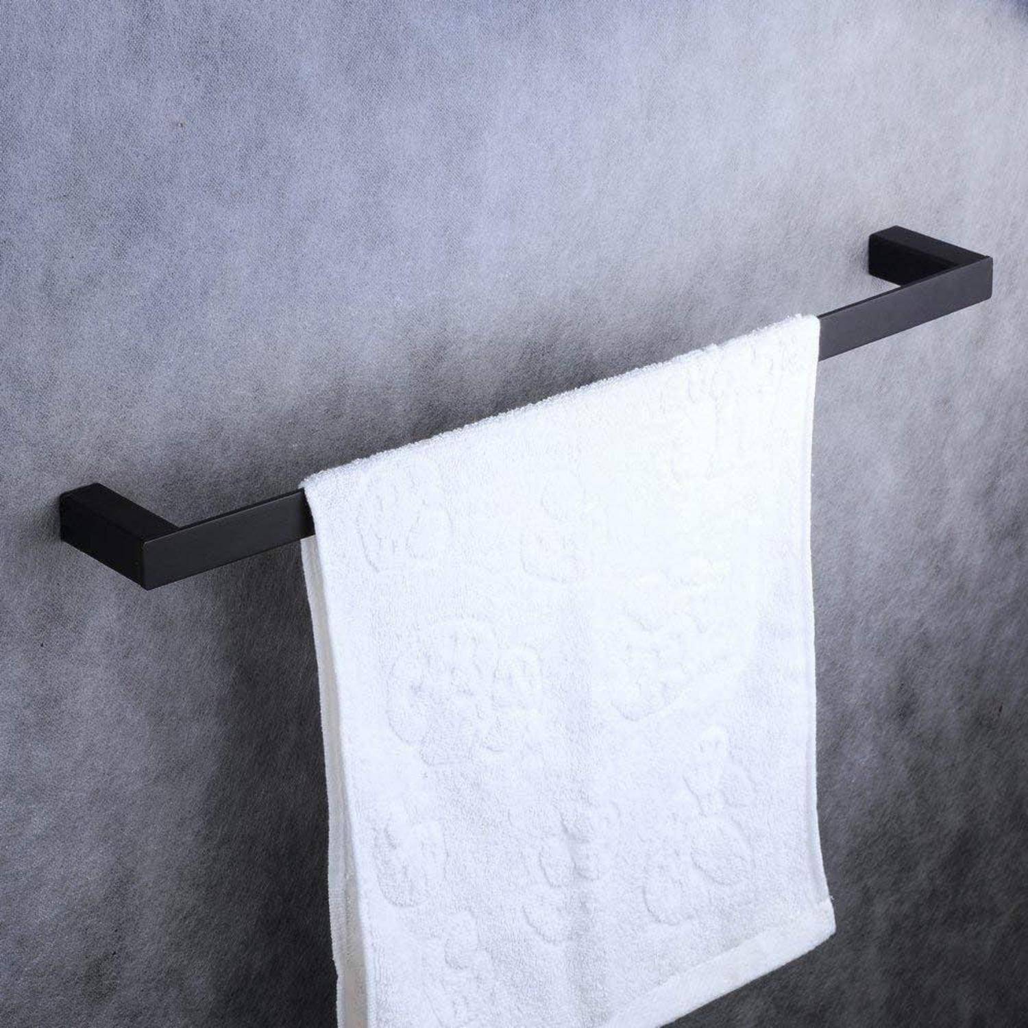 Weiches Handtuch, das auf einer schwarzen wandmontierten Handtuchstange an einer grauen strukturierten Wand hängt.