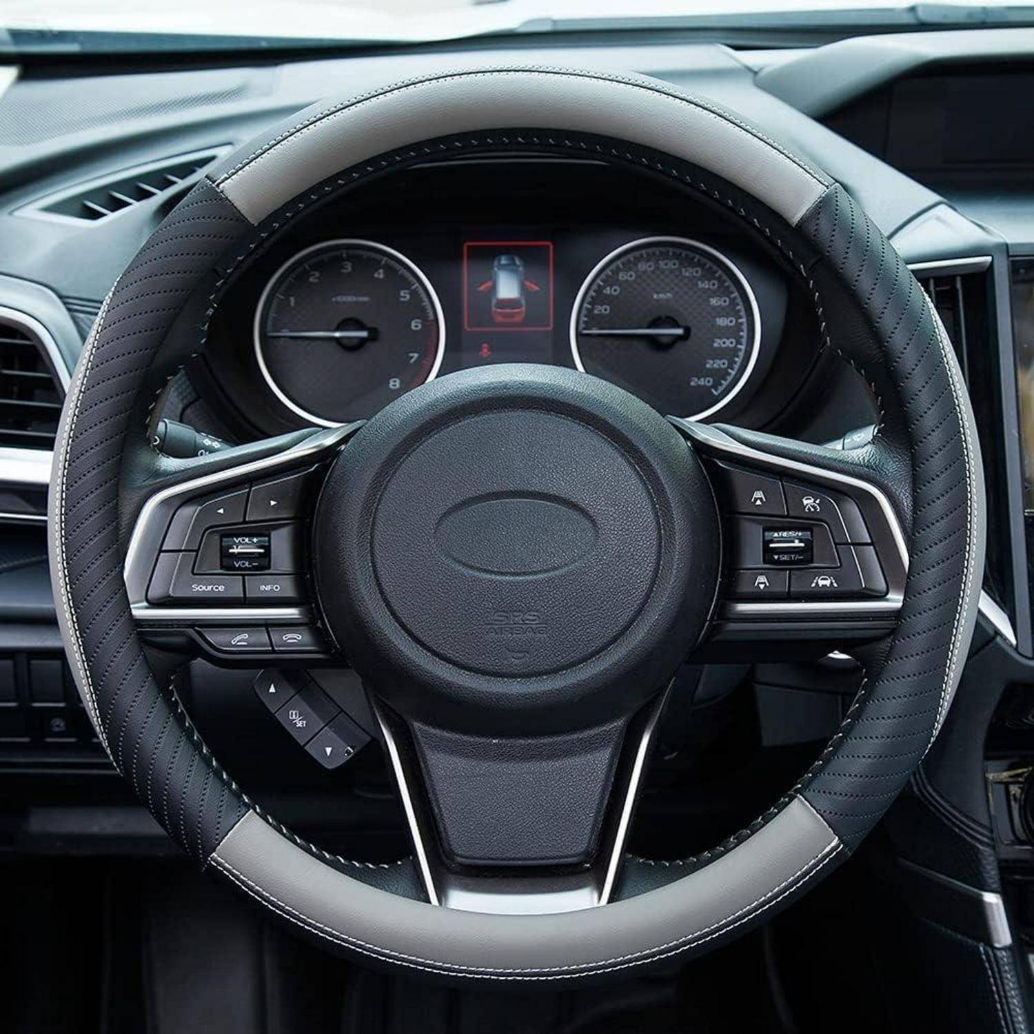 Nahaufnahme eines Autolenkrads mit integrierten Steuertasten und analogen Instrumenten dahinter, aus der Perspektive des Fahrersitzes betrachtet.