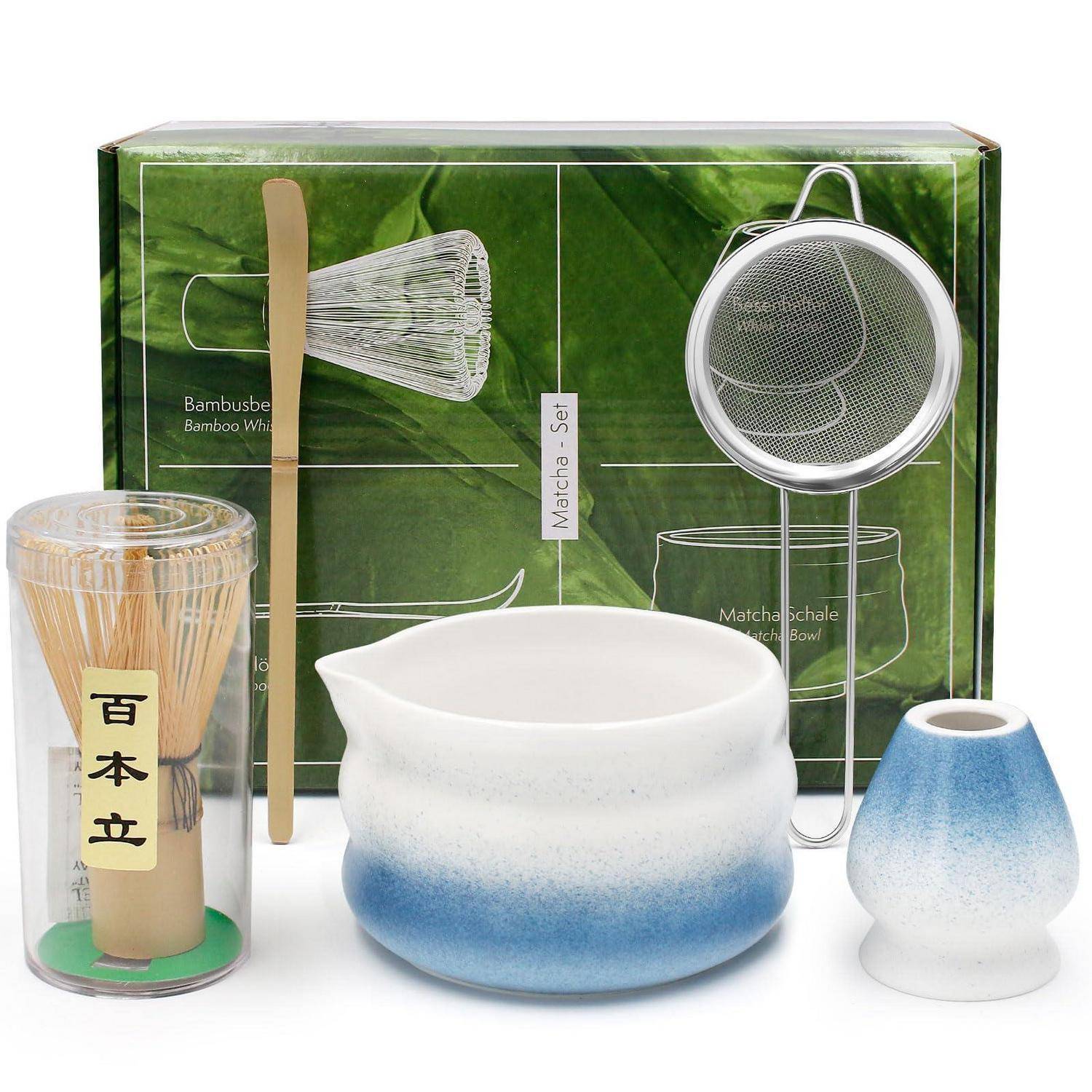 Matcha-Teeset mit Bamboosbesen, Metallsieb, Keramikschale und kleiner Tasse, präsentiert vor einer grünen Verpackungsbox.