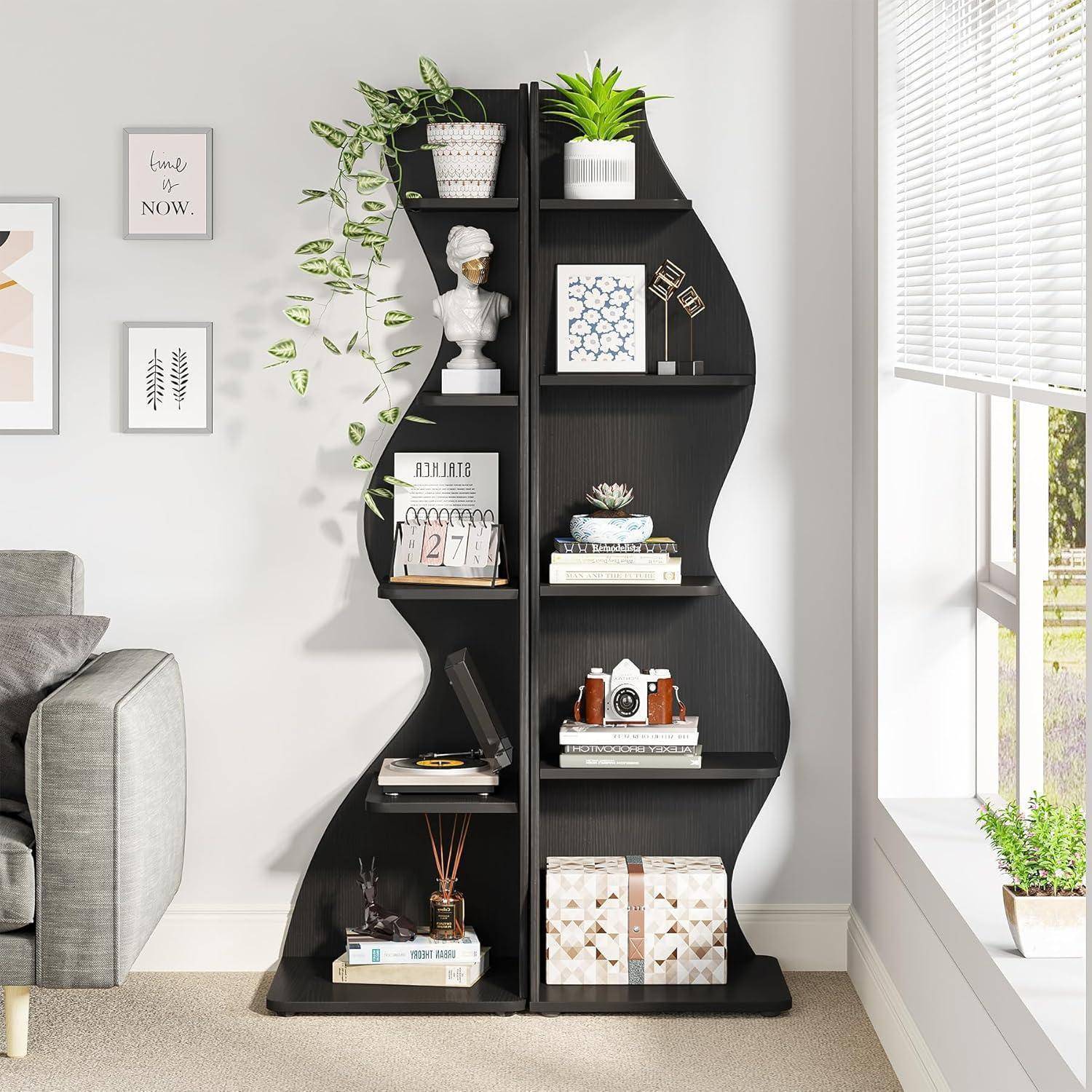 Schwarze wellige Regaleinheit mit Büchern, Pflanzen, gerahmter Kunst, Dekorationsobjekten und einer weißen Büste in einem hellen Wohnzimmer neben einem Fenster.