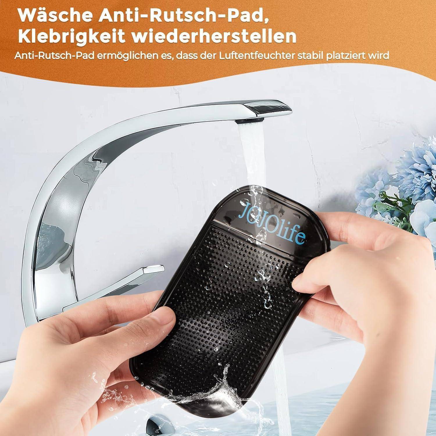 Hände spülen eine schwarze rutschfeste Matte unter fließendem Wasser, um ihre Griffigkeit wiederherzustellen, mit deutschem Text über das Waschen der Matte zur Stabilisierung eines Luftbefeuchters.