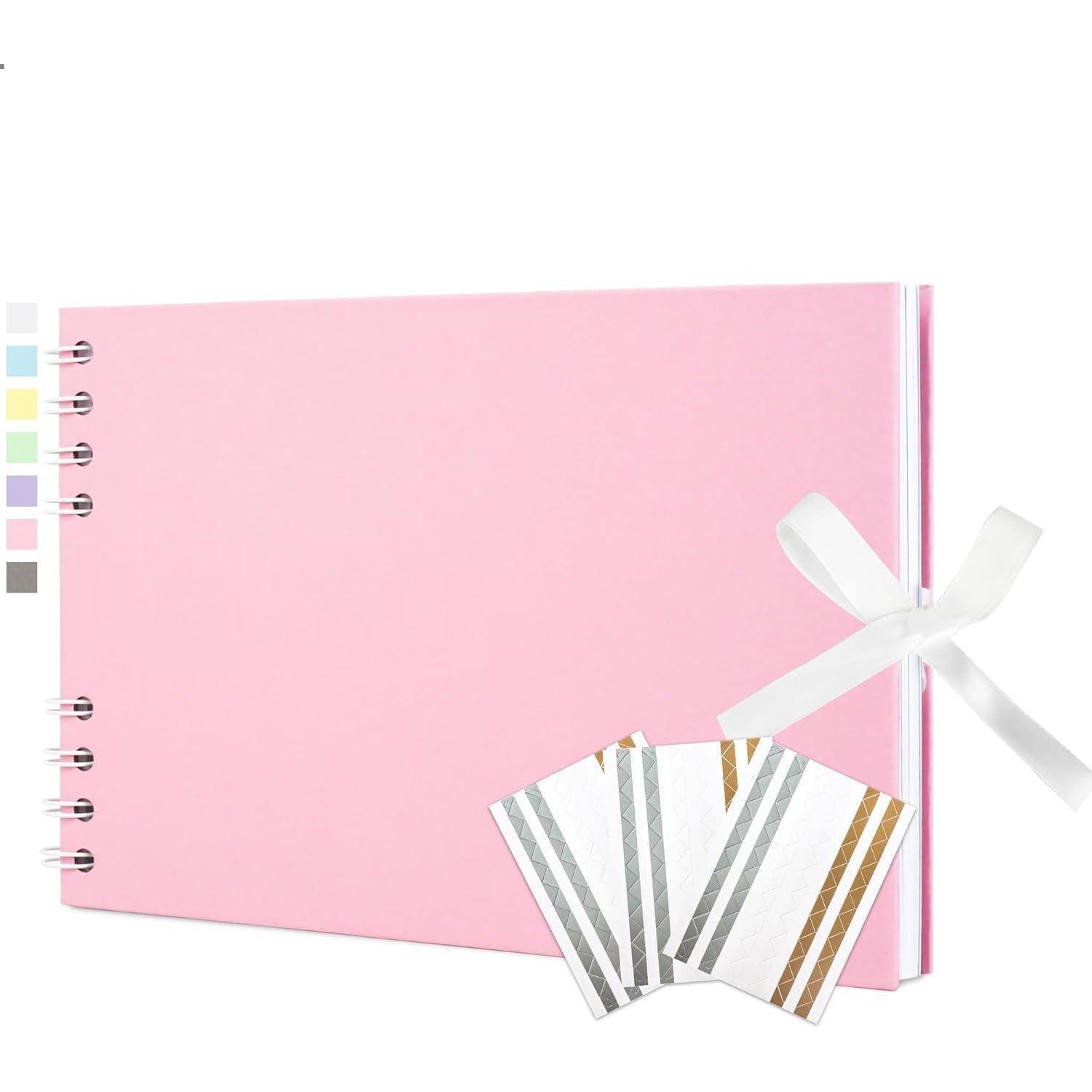 Rosa spiralgebundenes Notizbuch mit weißer Schleife und drei gestreiften Musterkarten davor, was ein Schreib- oder Scrapbooking-Thema andeutet.