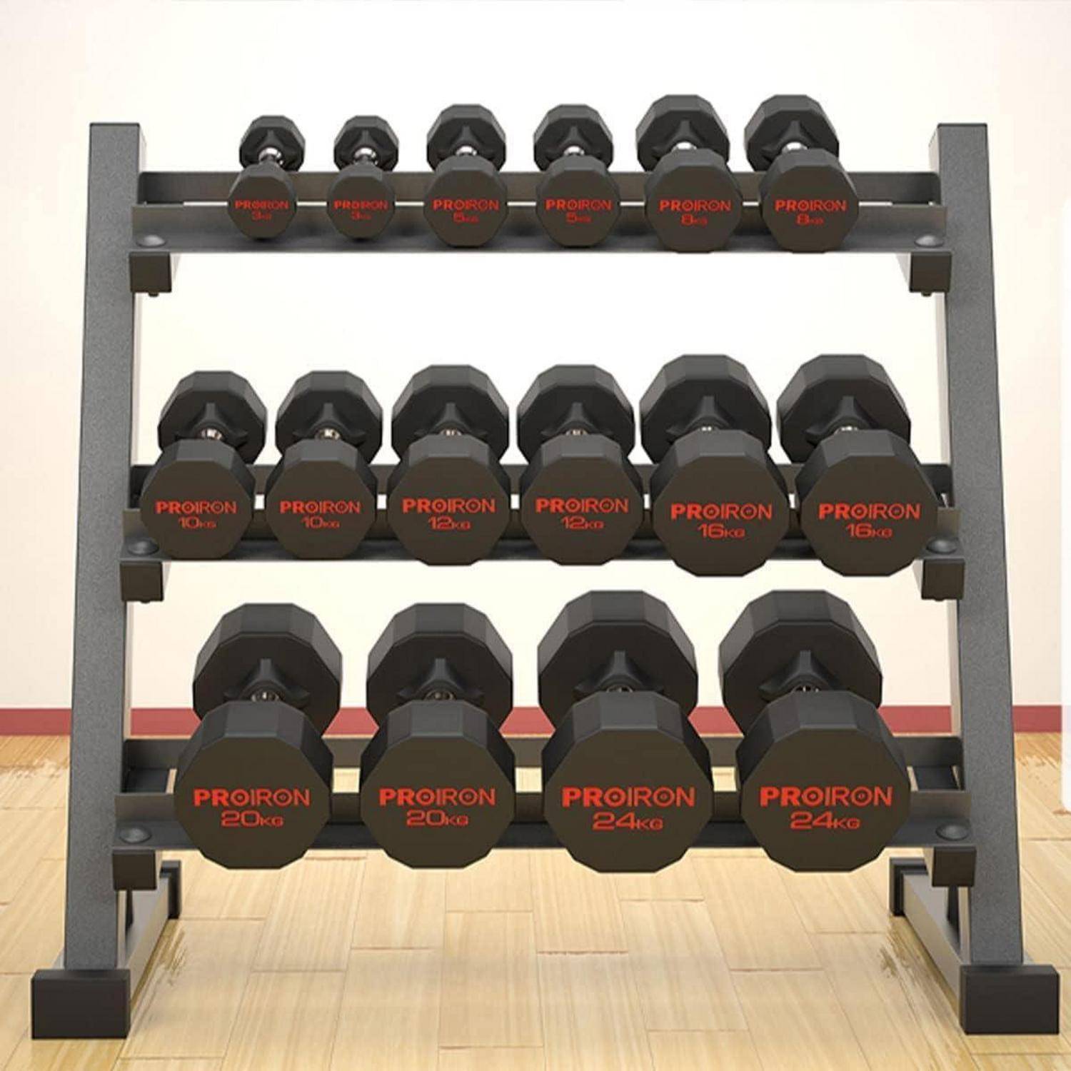 Dreilagiges Hantelgestell mit mehreren schwarzen sechskantigen Hanteln mit der Bezeichnung Proiron in einem Fitnessstudio auf einem Holzboden.