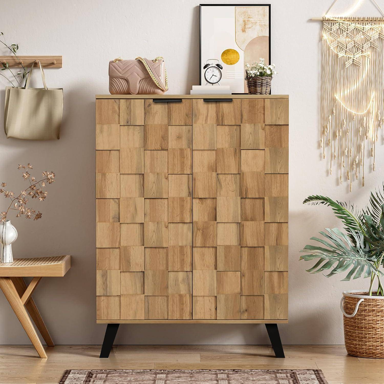 Holzschrank mit schwarzen Beinen in einem stilvollen Zimmer, oben mit einer Uhr, Bilderrahmen und Pflanzen verziert, flankiert von einer Wandtasche und Makramé-Dekoration.