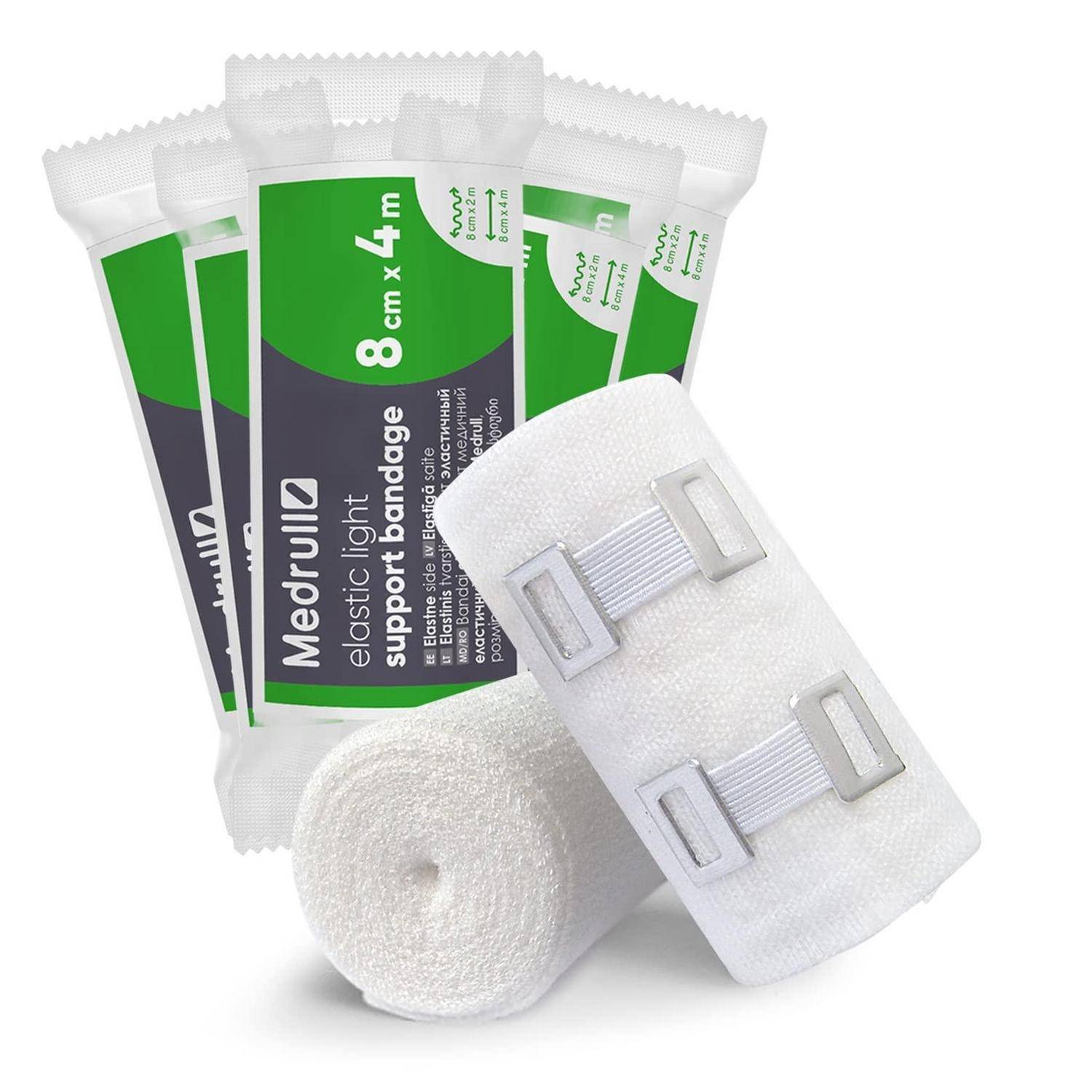 Medizinische Stützbandagen und elastische leichte Verbandrollenrollen, mit einer weißen Bandage mit Kunststoffverschlüssen im Vordergrund.