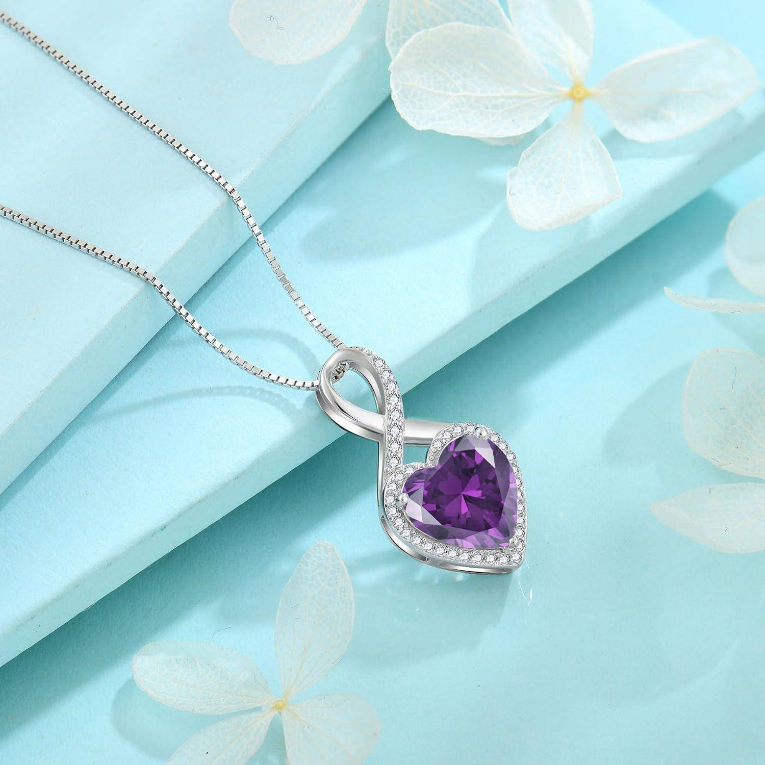Silberner Herzanhänger-Halskette mit einem violetten Edelstein auf hellblauem Hintergrund mit weißen Blumen.
