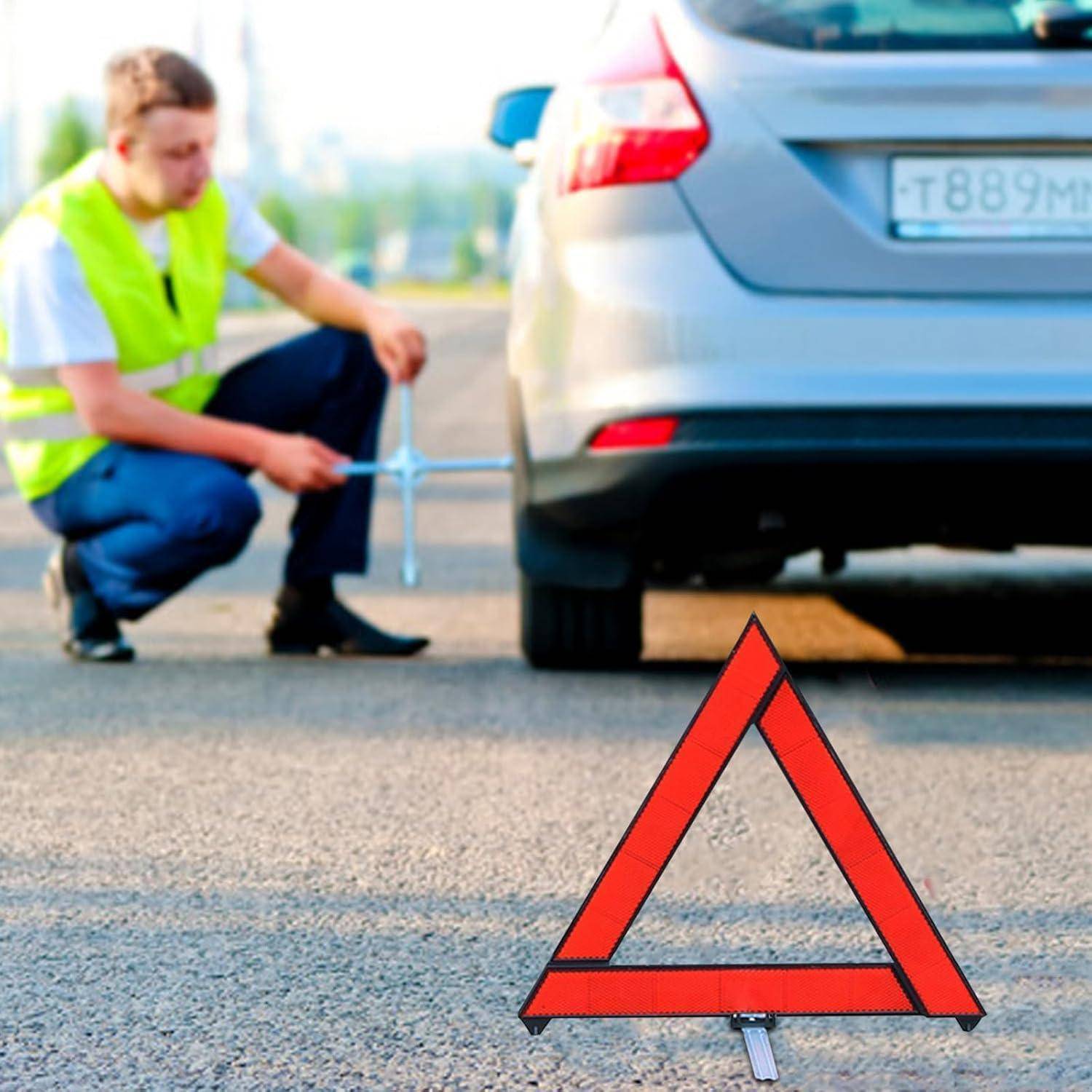 Szene am Straßenrand mit einem hockenden Arbeiter, der ein Hinterrad eines Autos inspiziert, mit einem roten Warndreieck im Vordergrund.