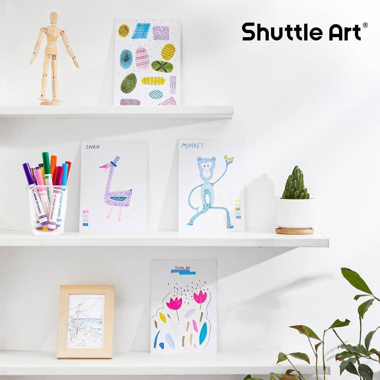 Weiße Regale präsentieren Kunstmaterialien und Zeichnungen für Kinder, darunter eine hölzerne Gliederpuppe, bunte Stifte, Tierzeichnungen, ein gerahmtes Foto und einen kleinen Topfkaktus unter dem Logo „Shuttle Art