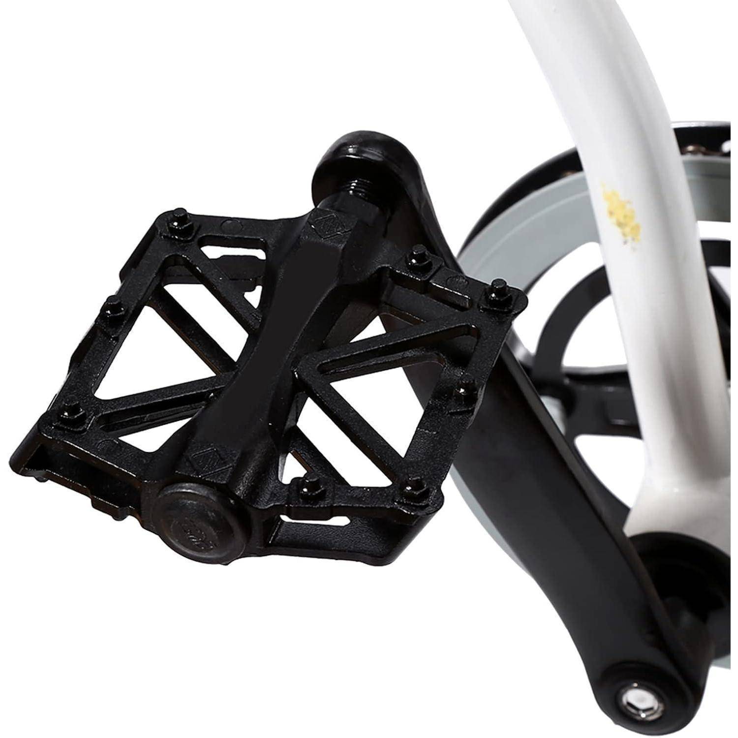 Nahaufnahme eines schwarzen Fahrradpedals, das an einem Kurbelarm befestigt ist, mit einem Teil eines Rades und einem weißen Rahmen, die auf weißem Hintergrund sichtbar sind.