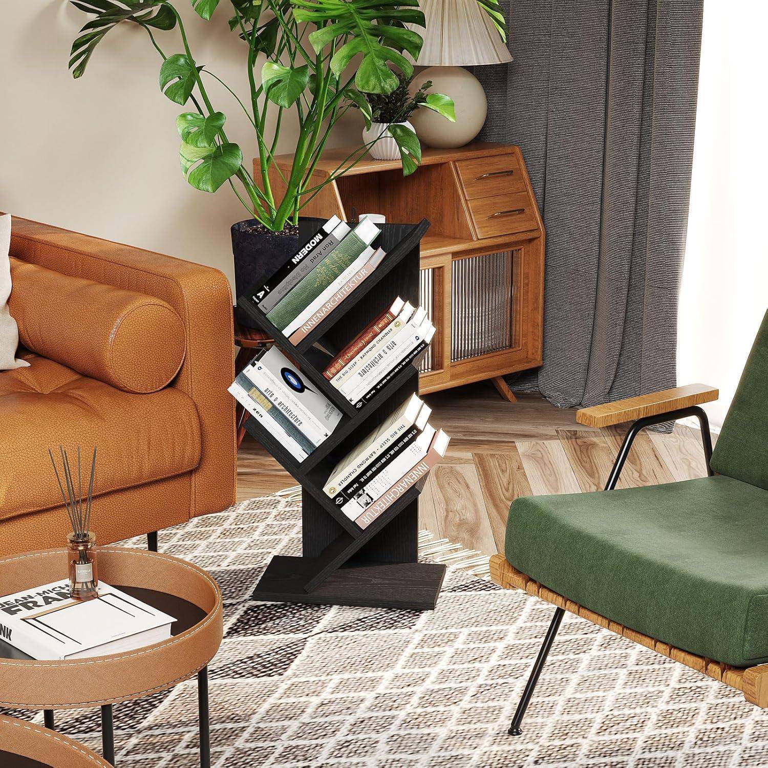Schwarzes Baumstil-Bücherregal mit Büchern in einem gemütlichen Wohnzimmer neben einem orangefarbenen Sofa, grünem Sessel, Topfpflanze und Holzschrank.