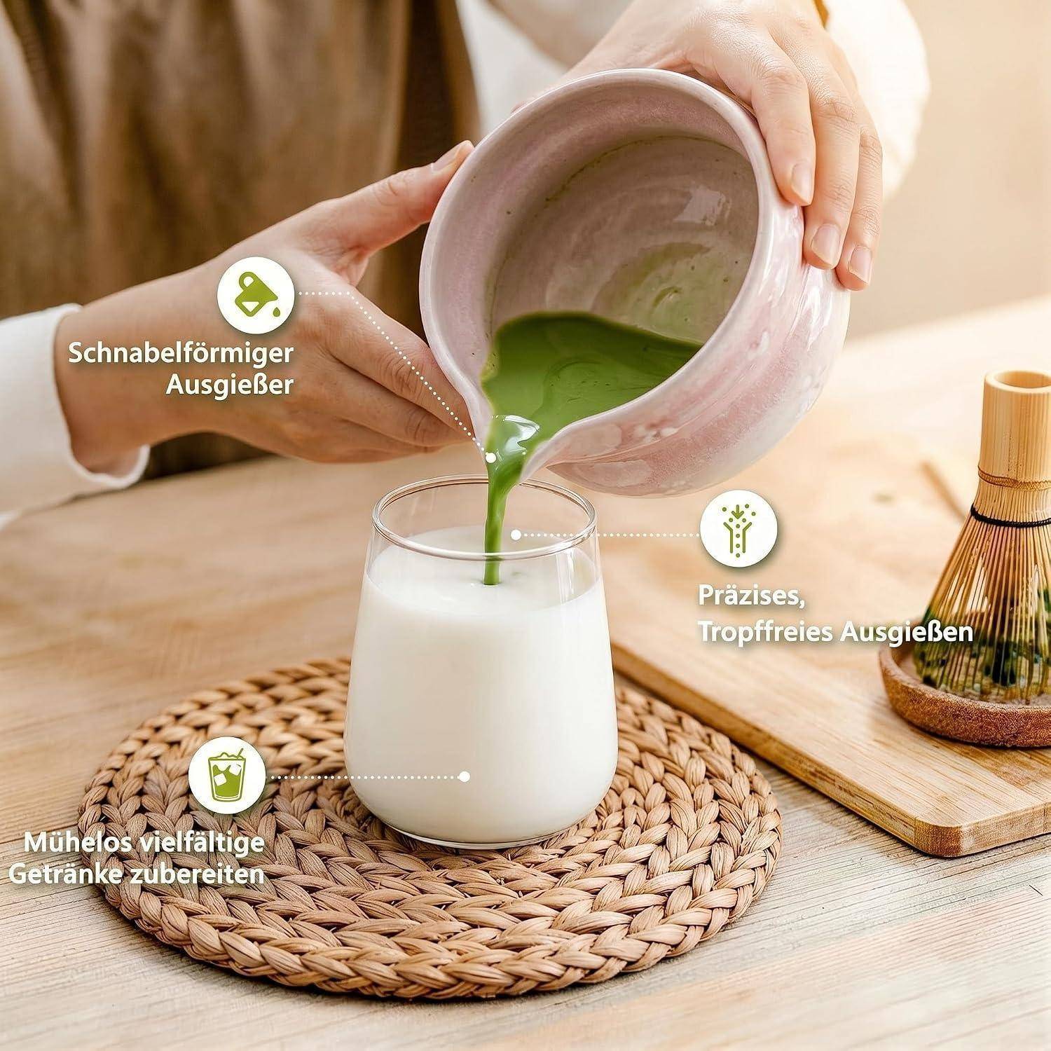 Hände gießen grünes Matcha aus einem Keramikkrug mit Ausguss in ein Glas auf einer geflochtenen Matte; deutsche Etiketten heben tropfenfreies Eingießen und vielseitige Getränkezubereitung hervor.