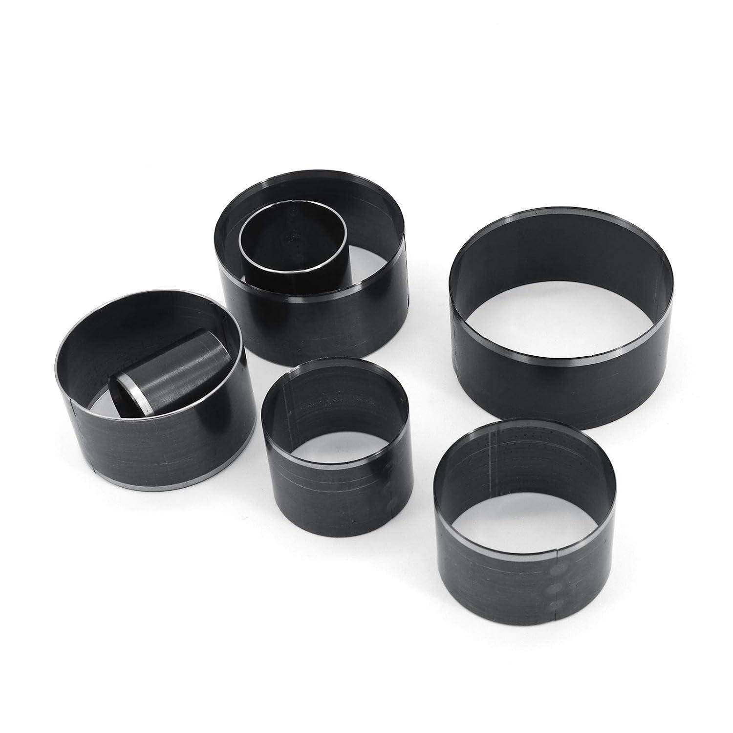 Fünf schwarze kreisförmige Metallringe verschiedener Größen auf weißem Hintergrund angeordnet, einschließlich eines Rings mit einem kleineren Einsatz im Inneren.
