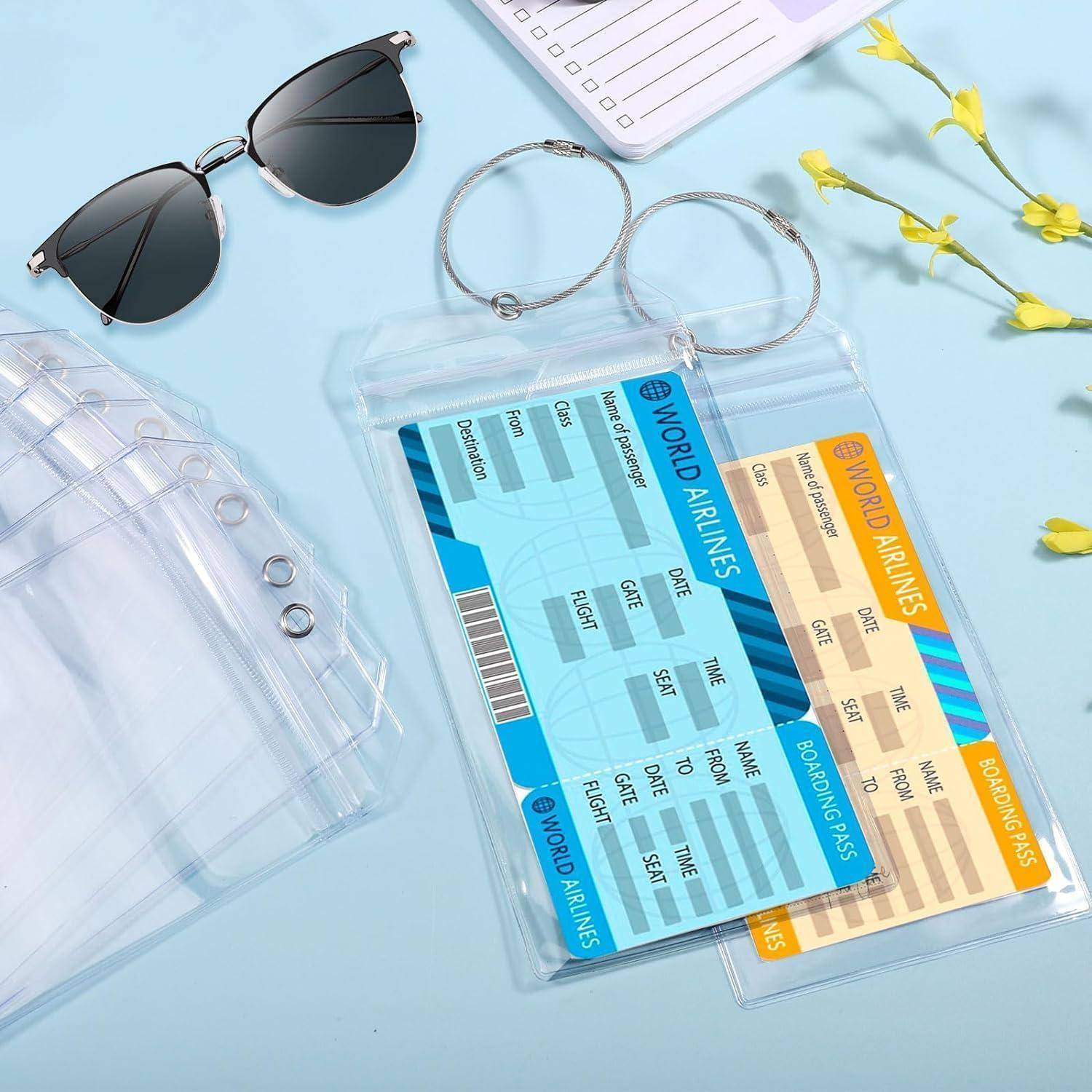 Reisezubehör auf einer blauen Oberfläche: durchsichtige Reisepassetuis halten eine Bordkarte und ein Ticket von World Airlines, zusammen mit einer Sonnenbrille, einer Lesebrille und einem Checklisten-Notizbuch.