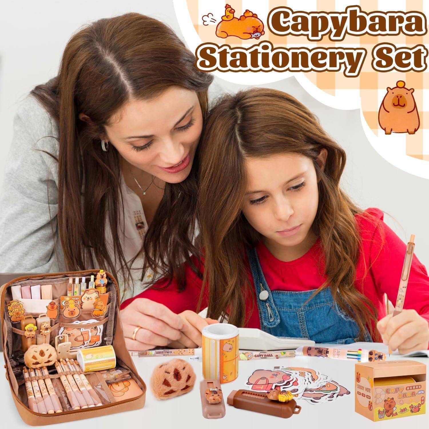 Frau und Mädchen verwenden ein Capybara-Schreibwaren-Set mit Stiften, Aufklebern, Klebeband und einem Aufbewahrungskoffer auf einem Tisch.