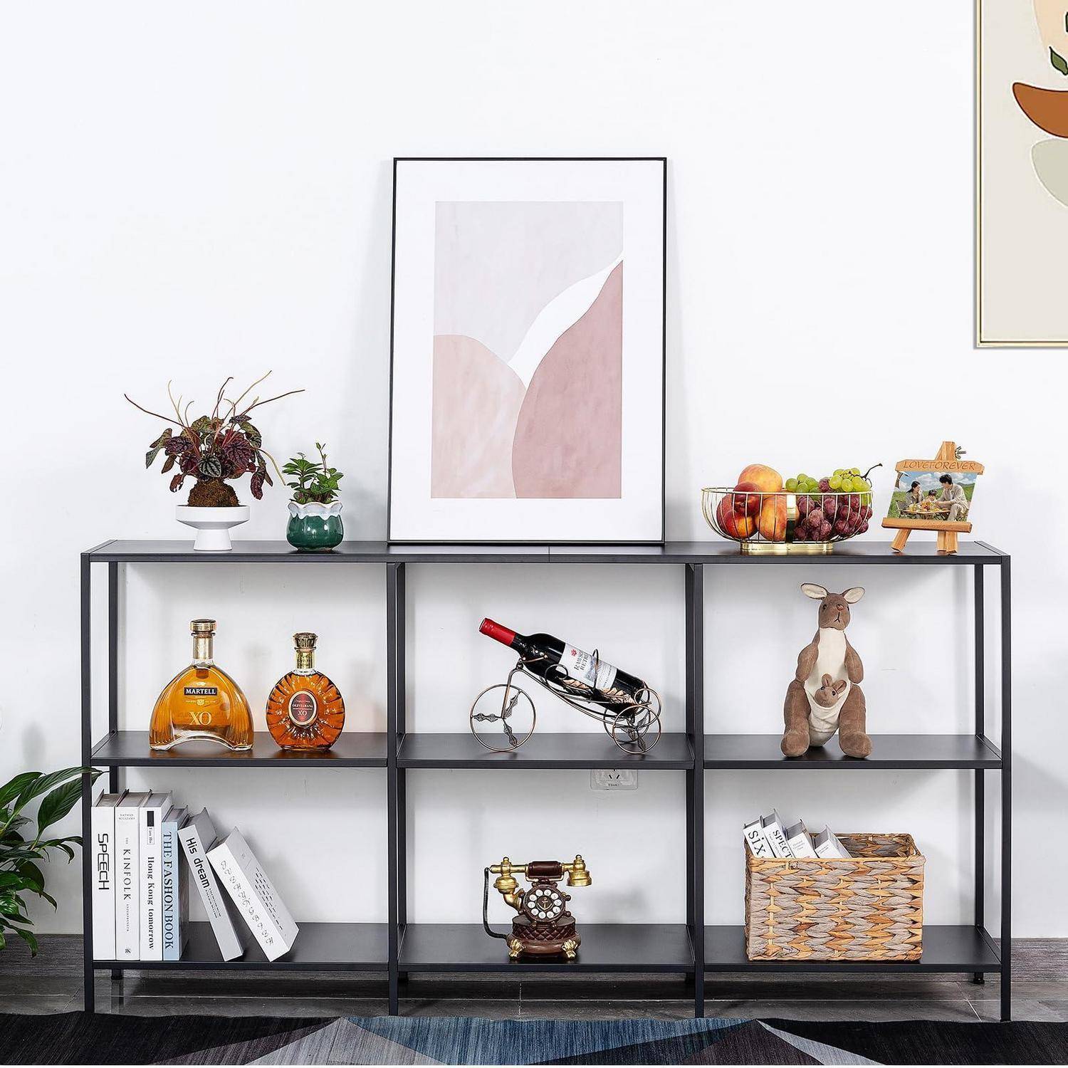 Schwarzes Metall-Konsolenregal an einer weißen Wand, gestylt mit gerahmter Kunst, Pflanzen, Flaschen mit Spirituosen, Obstkorb, Büchern, Spielzeug, Vintage-Telefon und Weidenkorb.